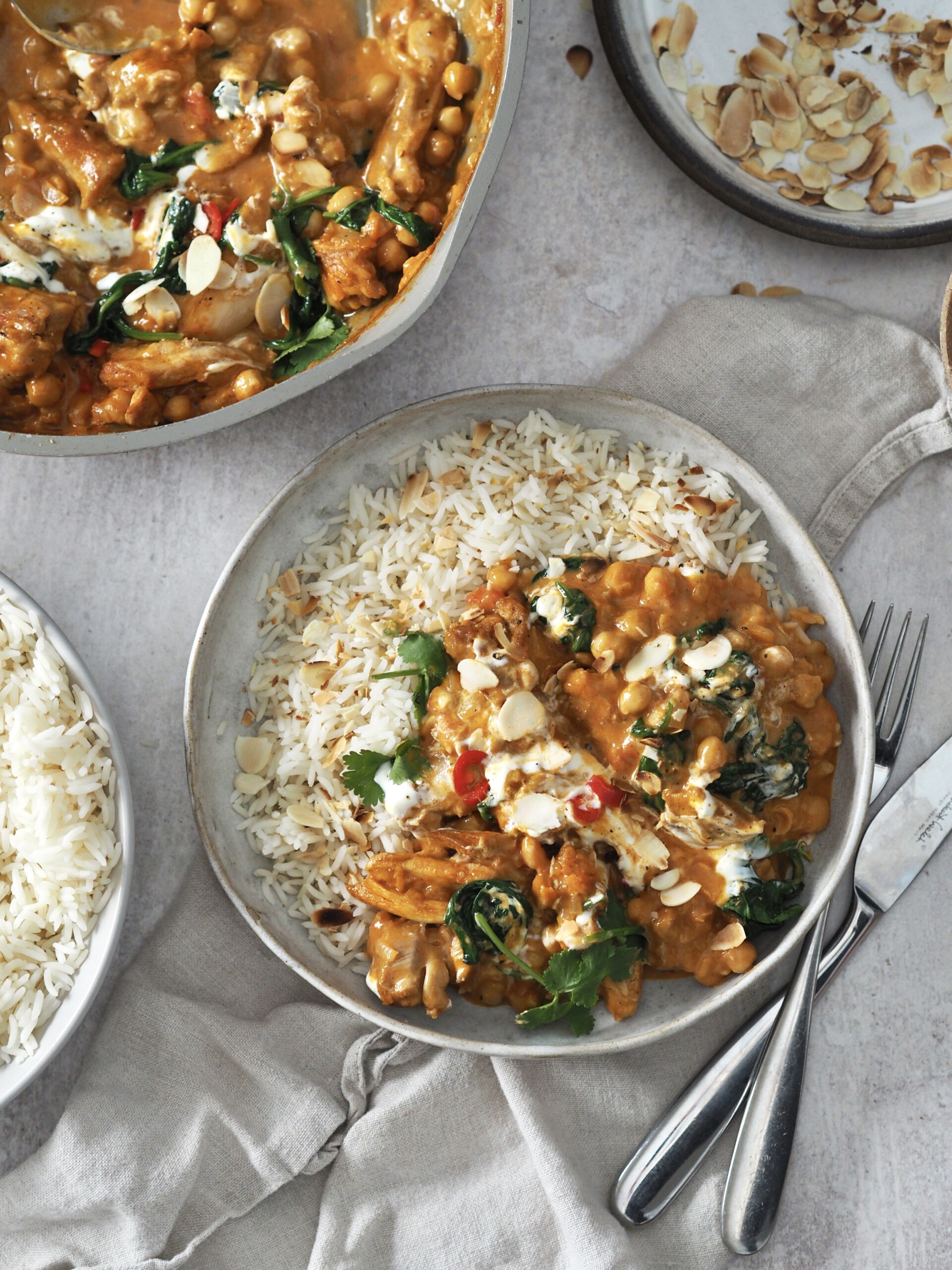 chicken and chickpea curry garnished with yoghurt and herbs served with rice.