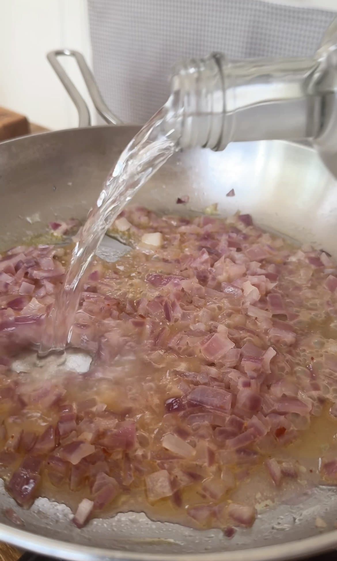 adding vodka to the onions for vodka pasta.