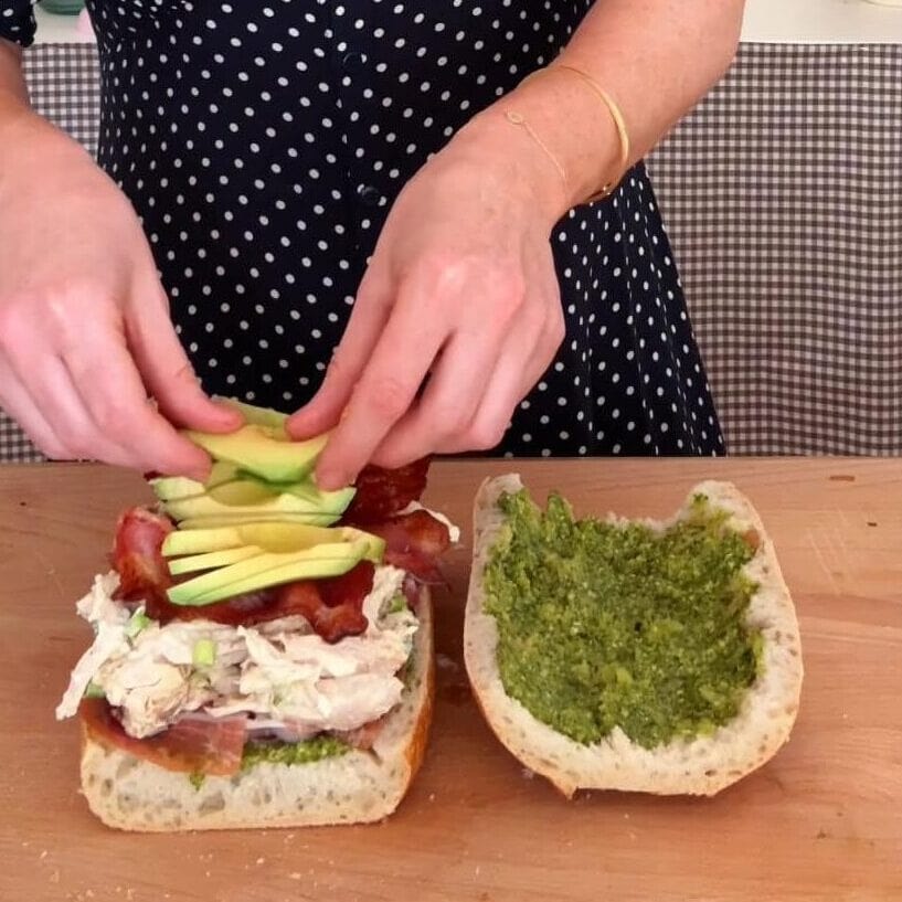 adding avocado to the sandwich.