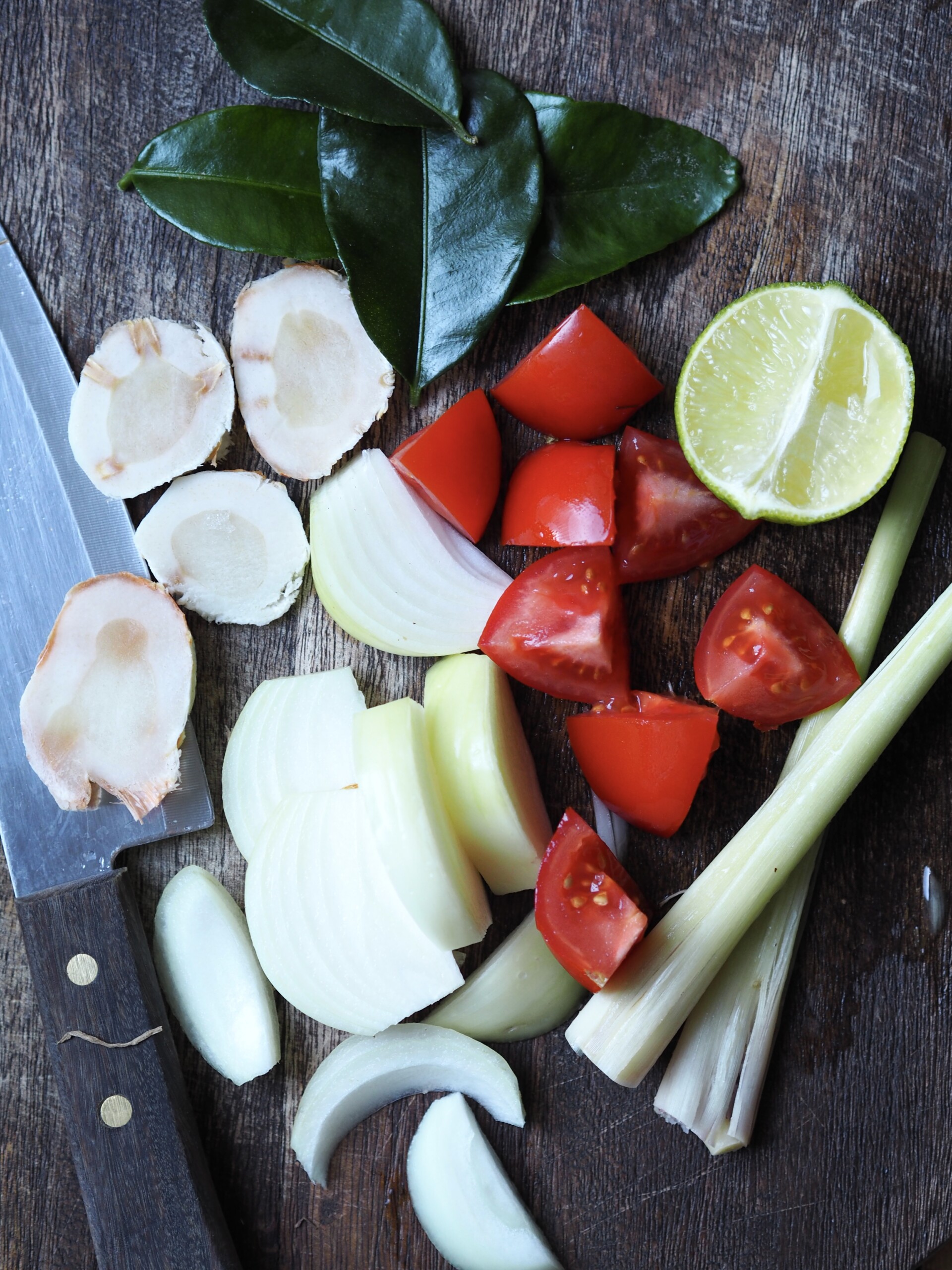 chicken tom yum soup ingredients on a wooden chopping board.