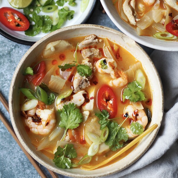 chicken tom yum soup in a white bowl with chilli and coriander on top.