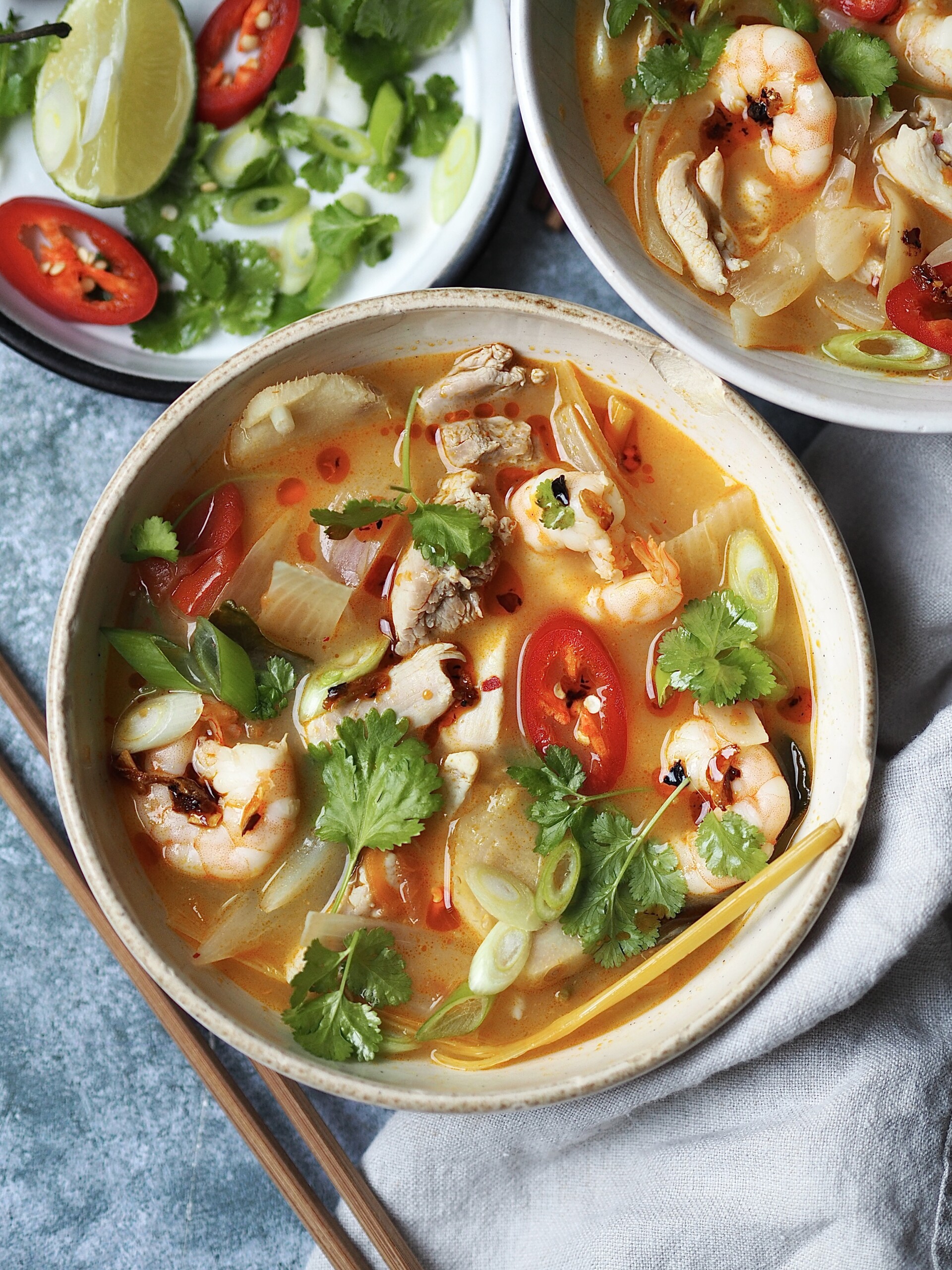 chicken tom yum soup in a white bowl with chilli and coriander on top.