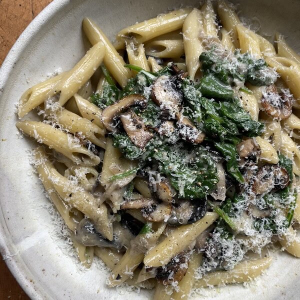 creamy mushroom and spinach pasta in a grey bowl.