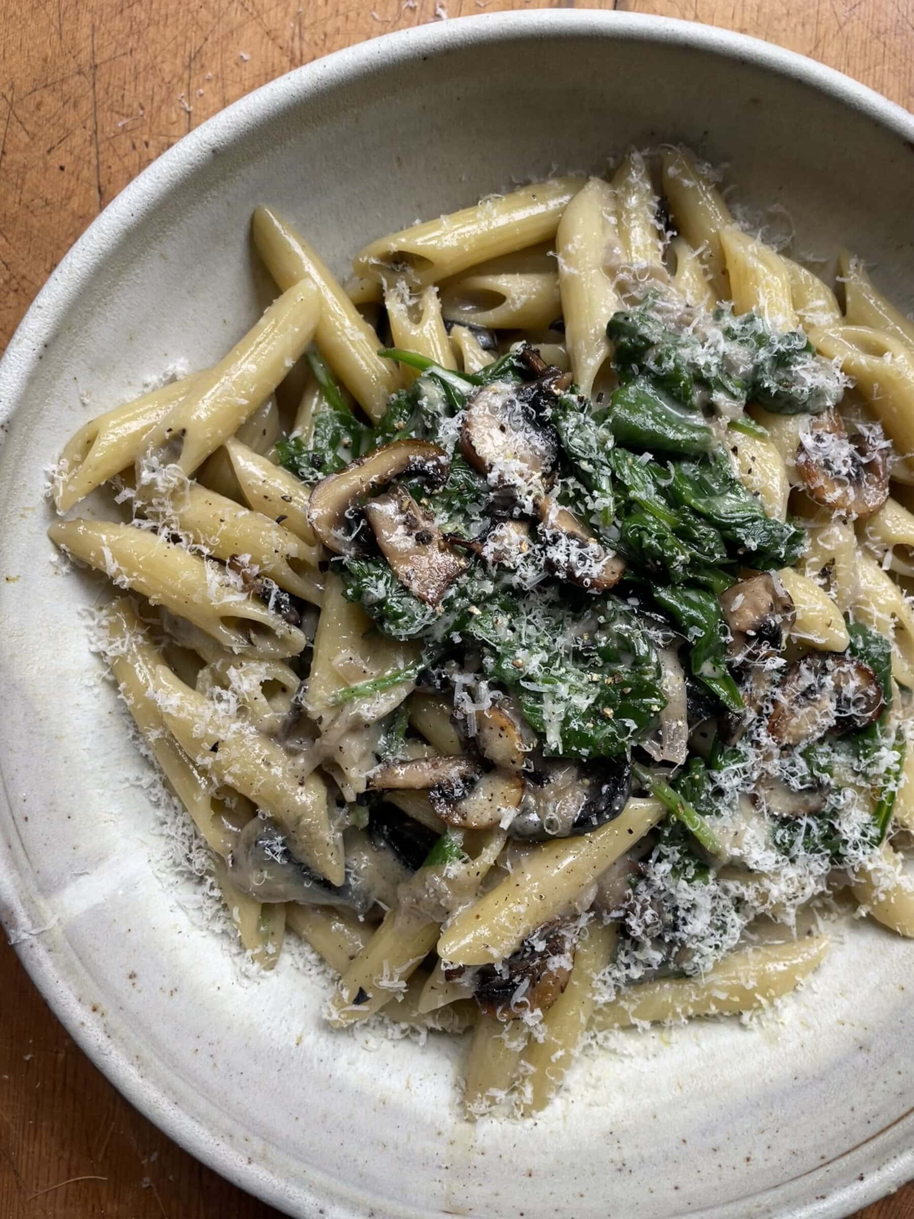 creamy mushroom and spinach pasta in a grey bowl.