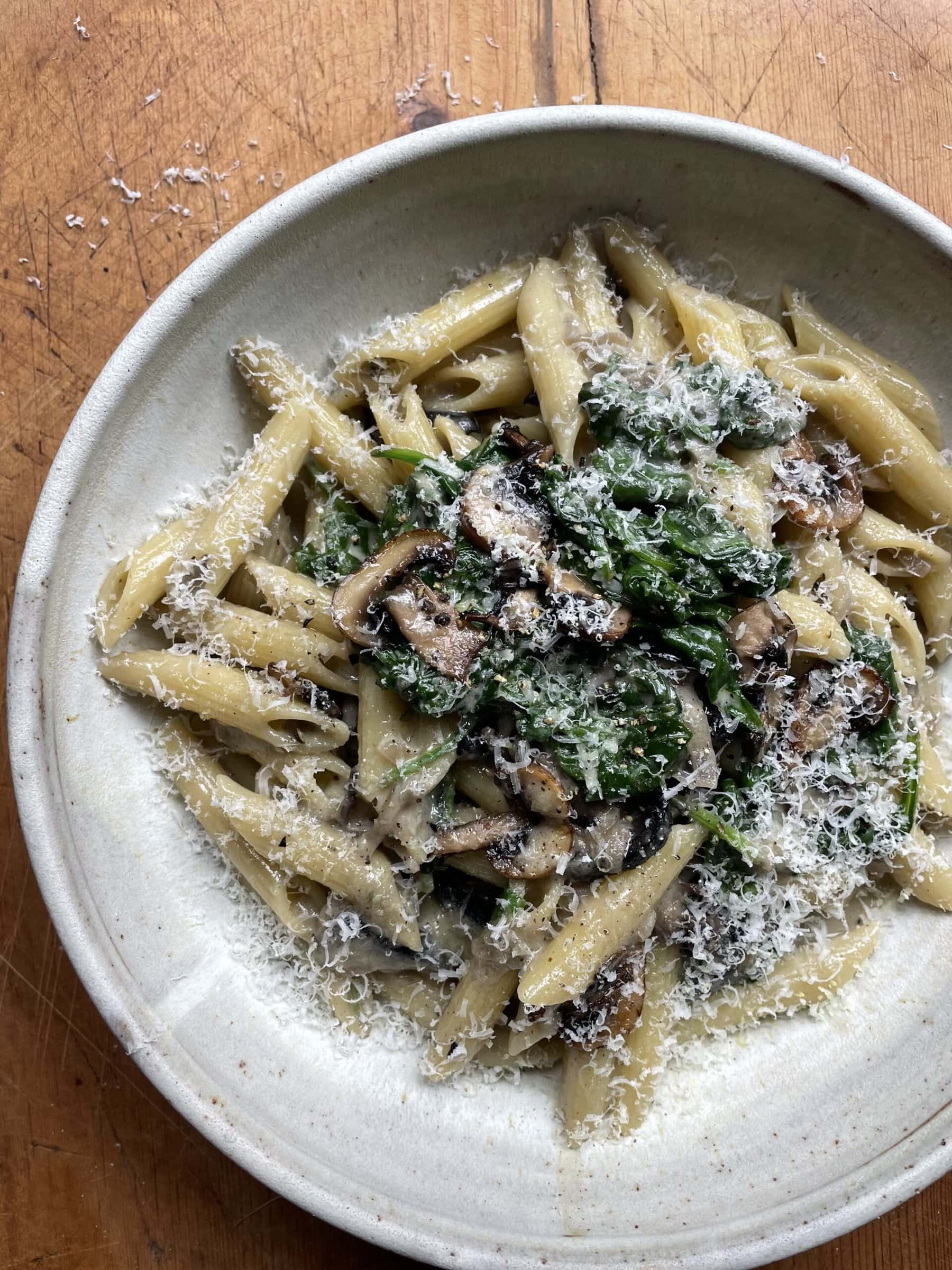 creamy mushroom and spinach pasta in a grey bowl.