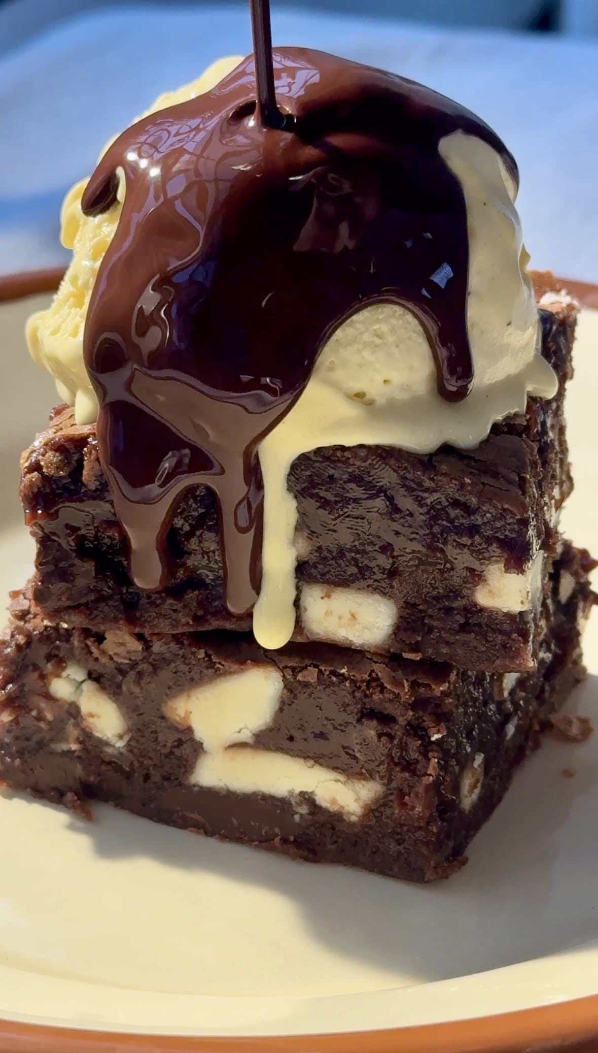 chocolate and white chocolate brownies stacked with ice cream on top.