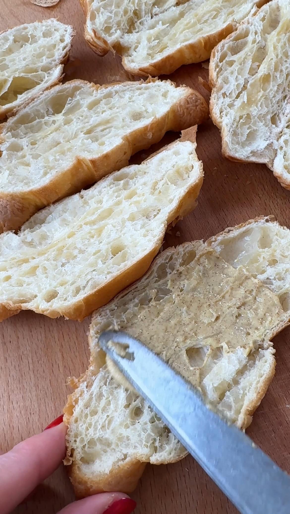 adding mustard to sliced croissants.