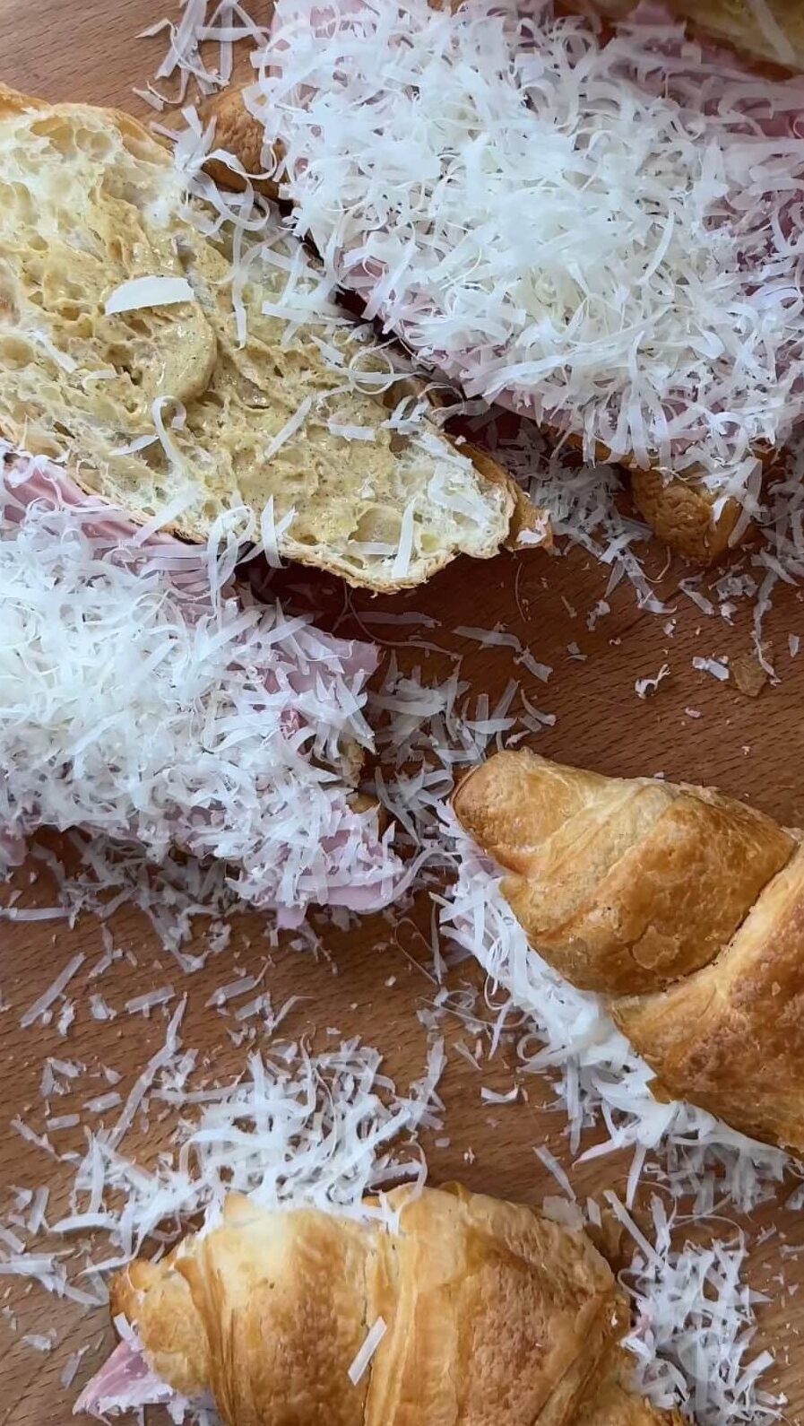 grating cheese over the croissant sandwiches.