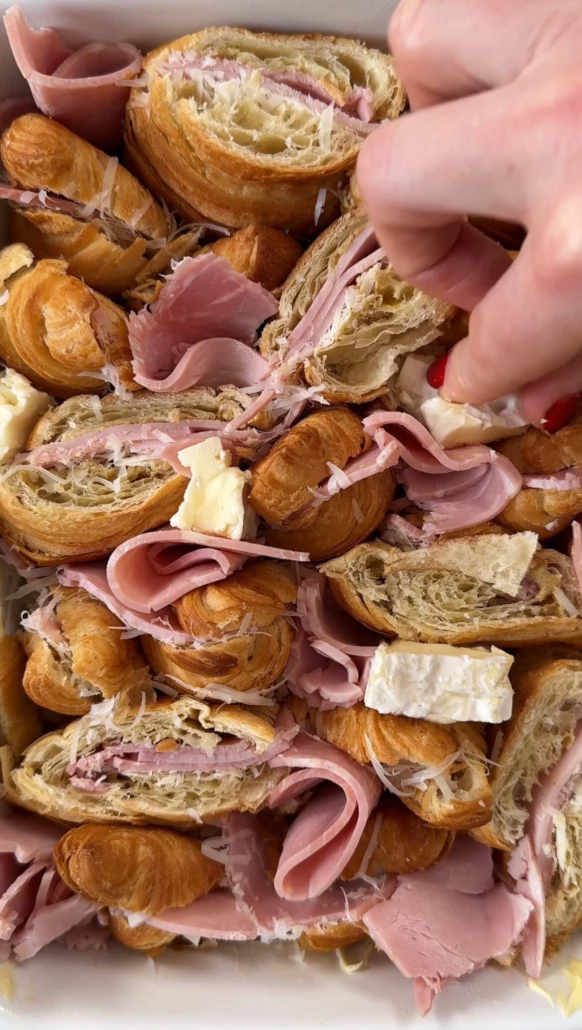 adding brie to the ham and cheese croissant bake.