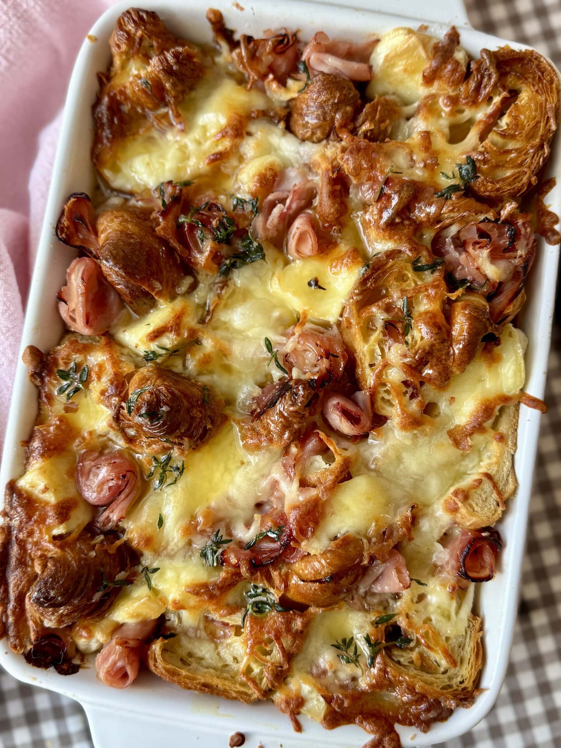 ham and cheese croissant bake in a white baking dish.