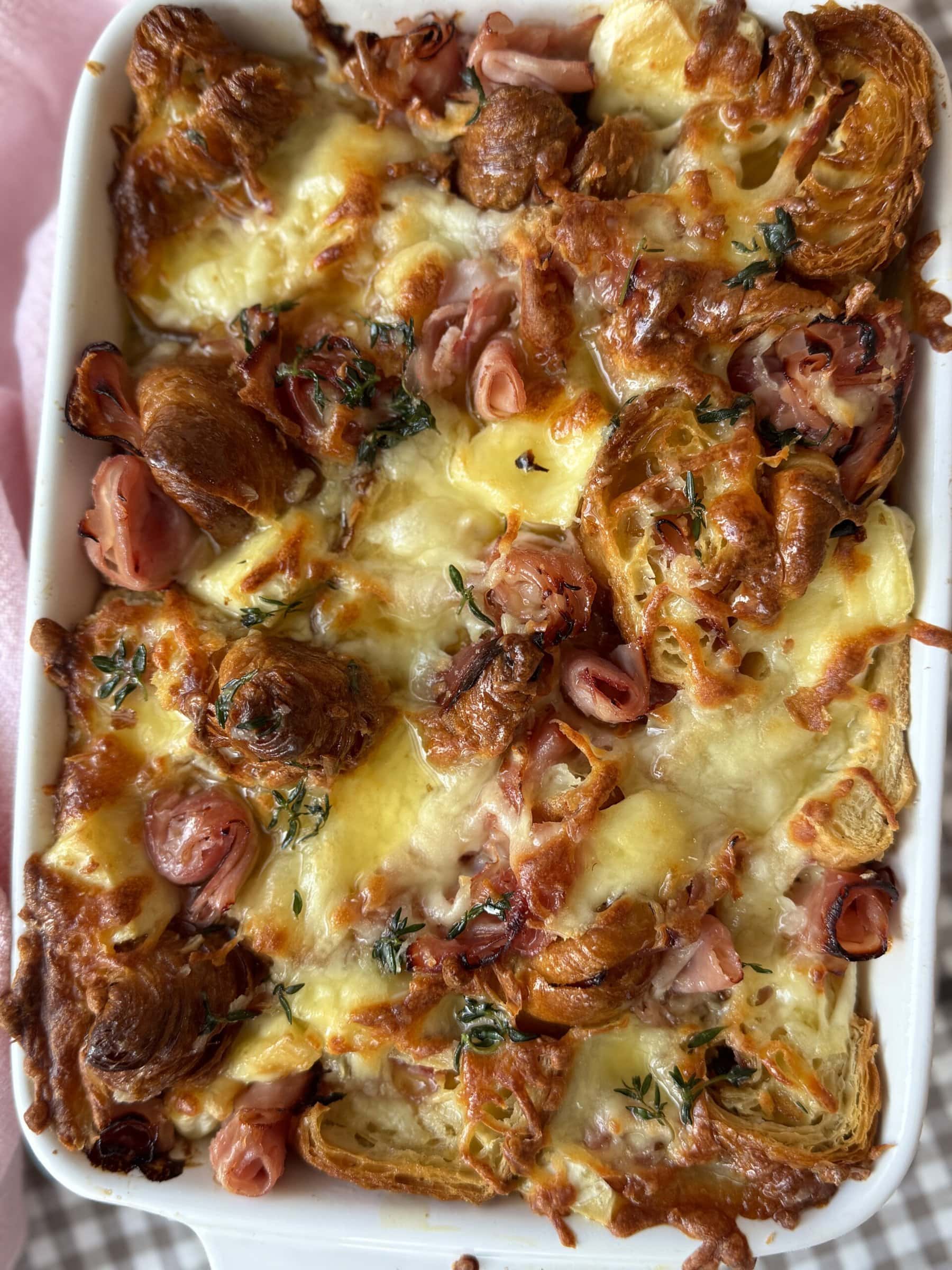 ham and cheese croissant bake in a white baking dish.