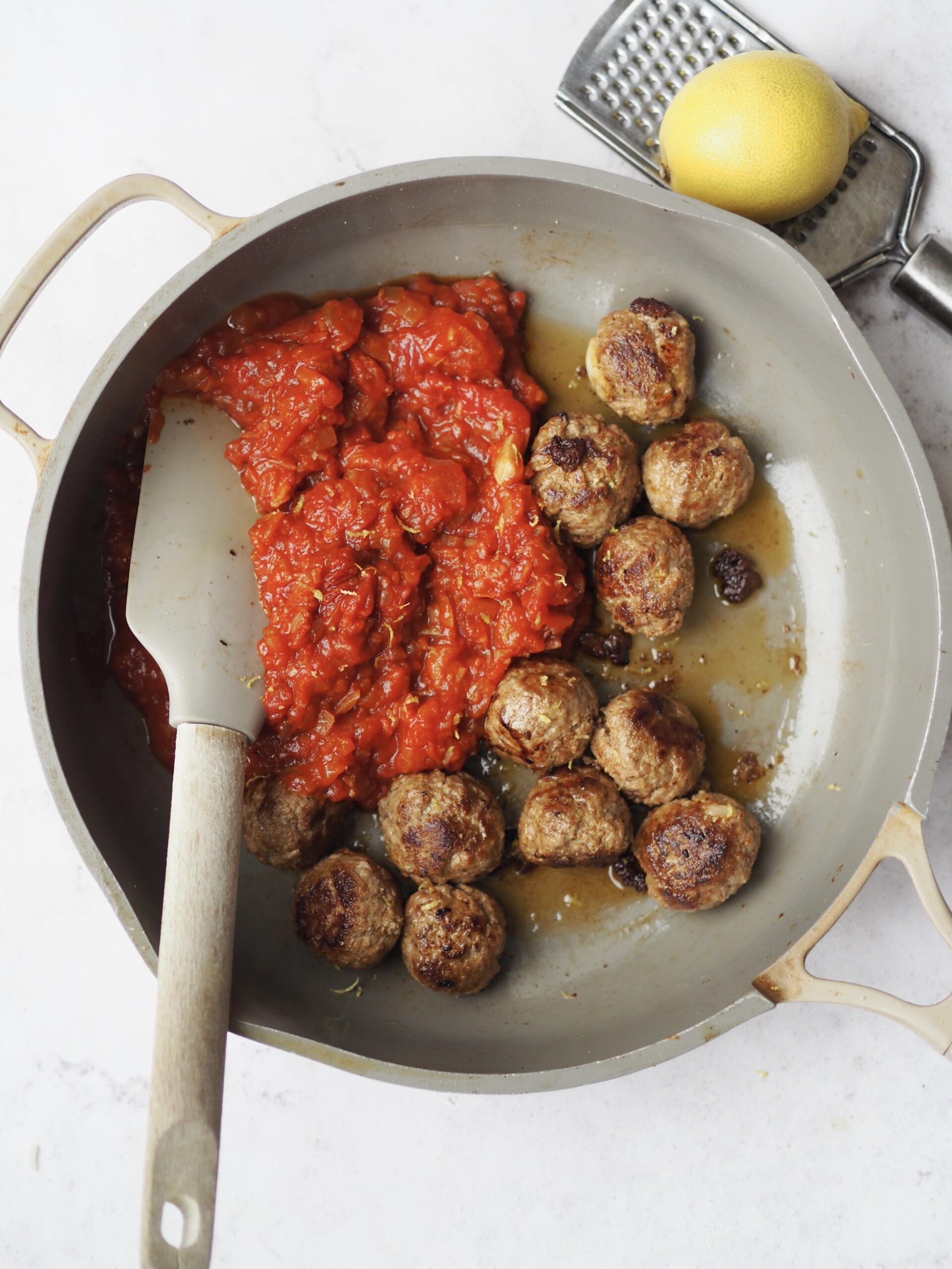 adding meatballs to tomato sauce.