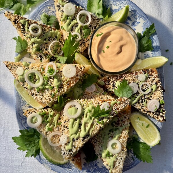 sesame prawn toasts with limes and green sauce drizzled on top.