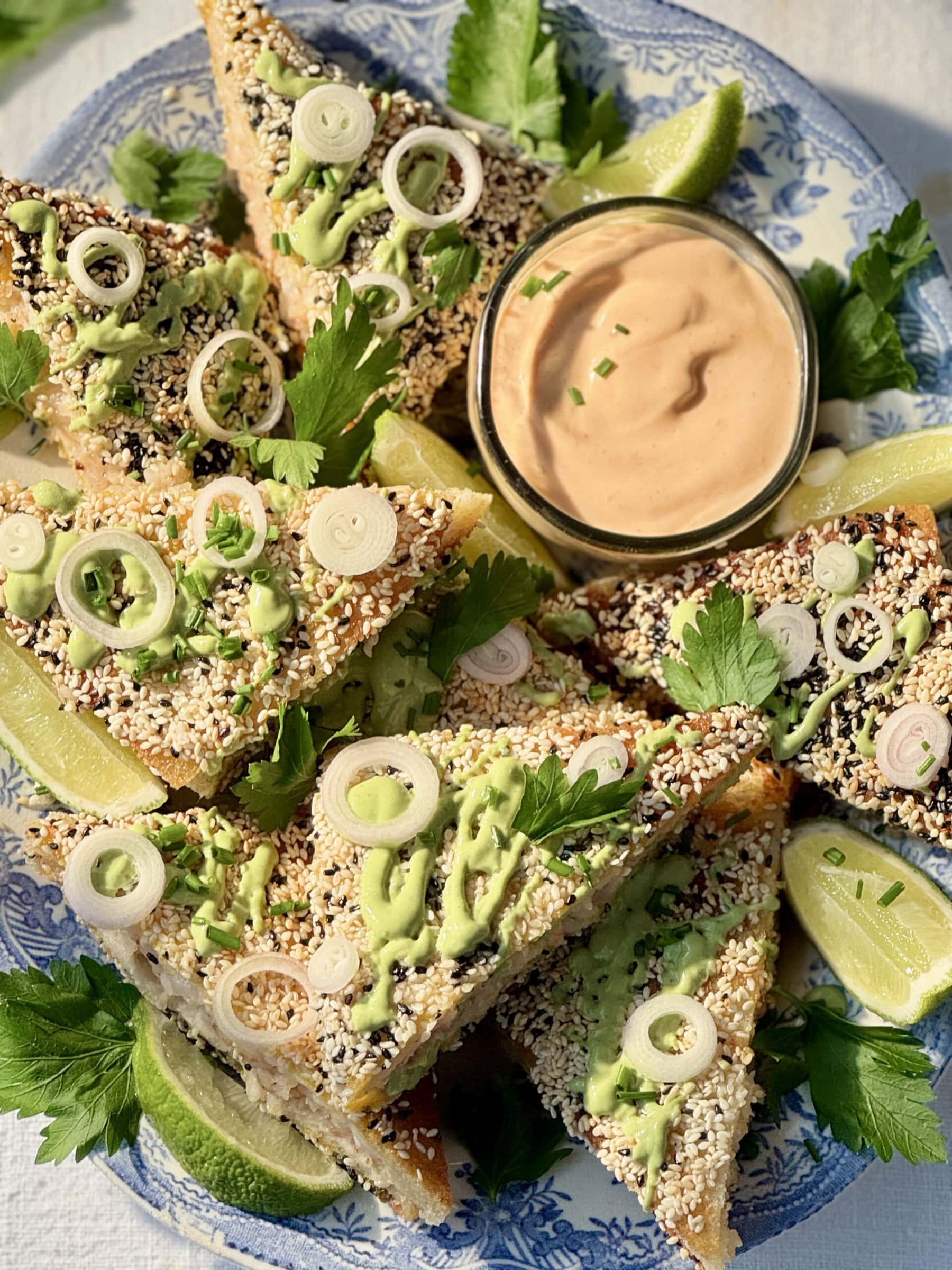 sesame prawn toasts with limes and green sauce drizzled on top.