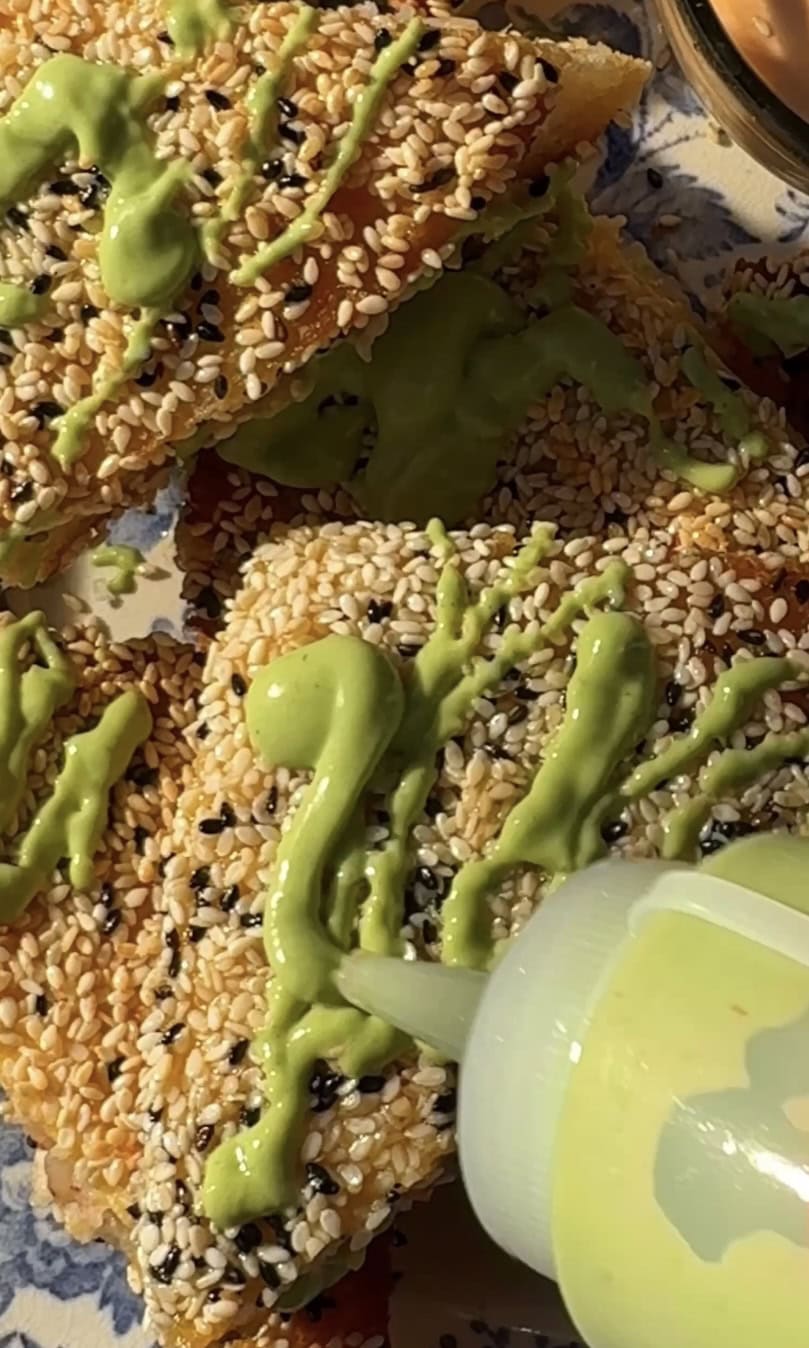 adding green sauce on the sesame prawn toasts.