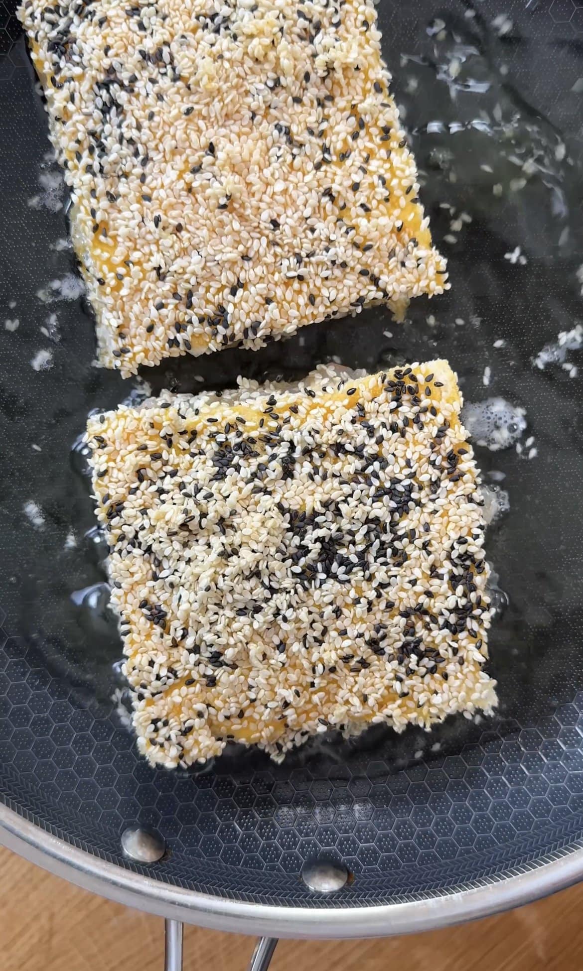 frying sesame prawn toasts in oil.