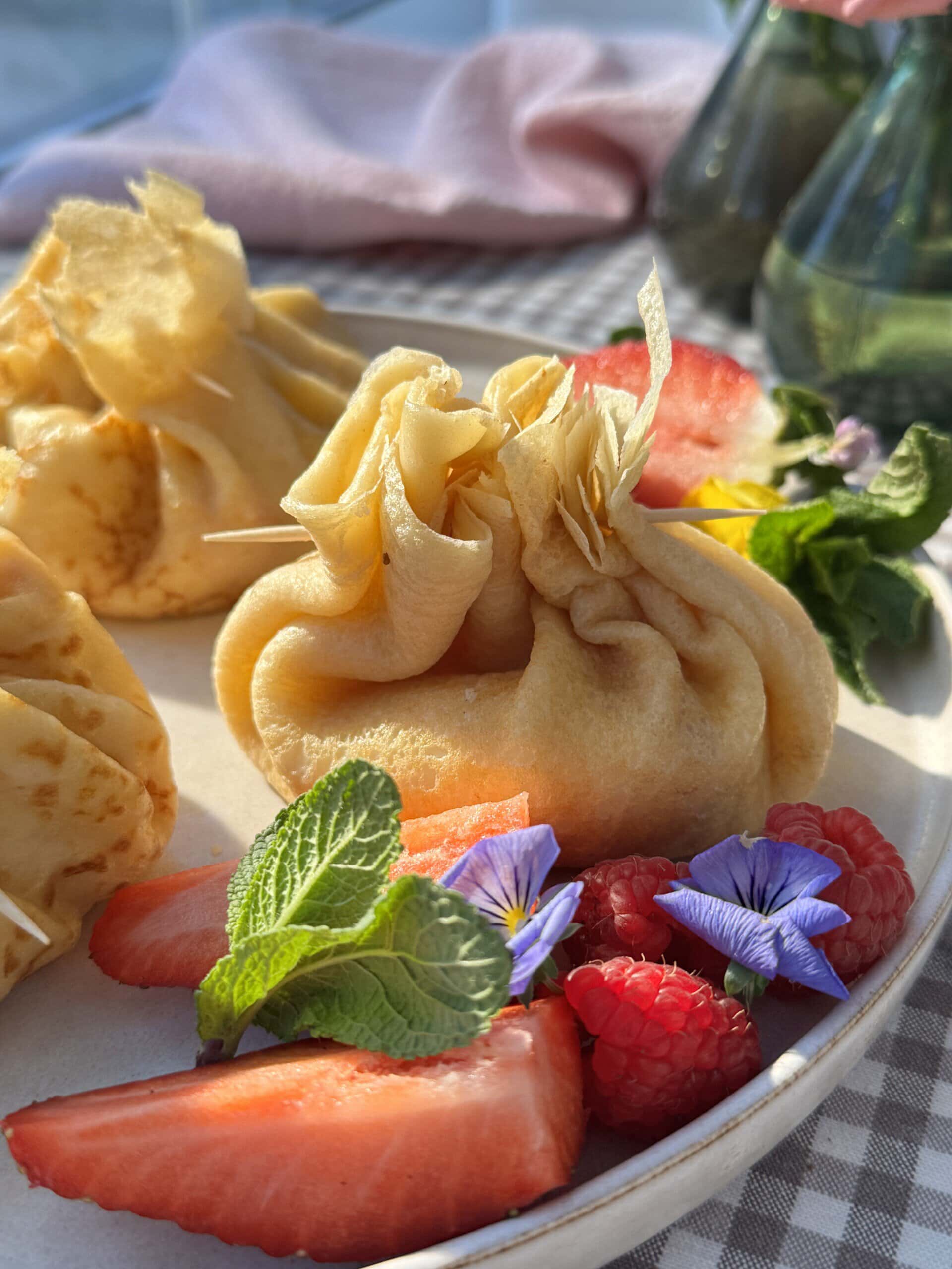 aumonieres de crepes on plate with fresh strawberries.