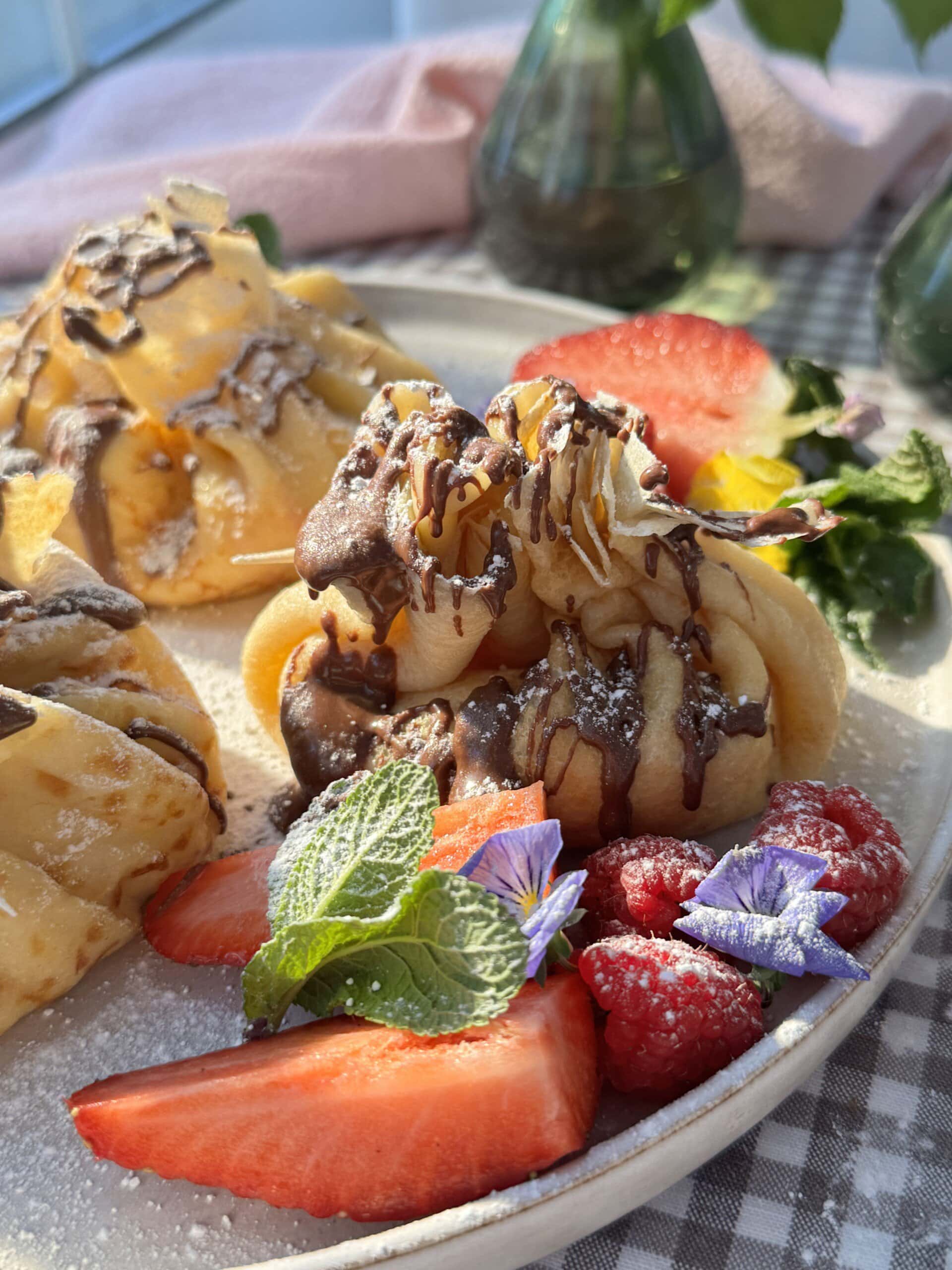 aumonieres de crepes on plate with nutella drizzled over the top.