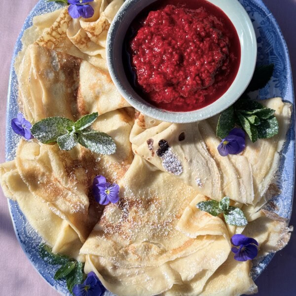 pannekaken on blue plate with raspberry compote.