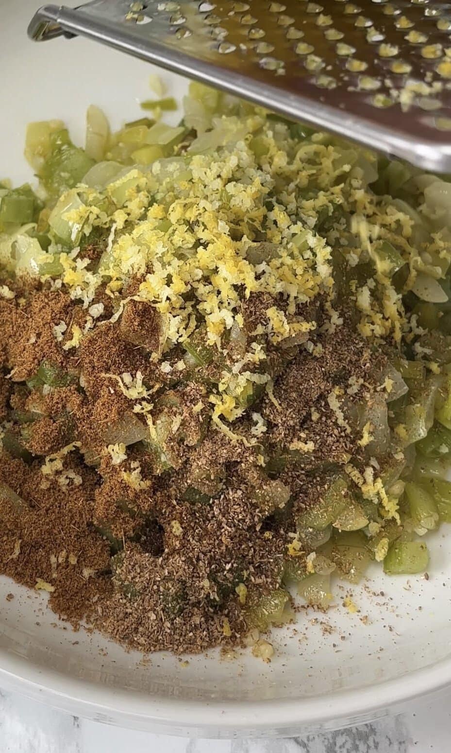 adding lemon zest to the vegetables for the couscous.