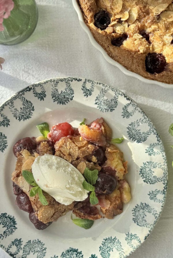 clafoutis aux cerises in a bowl with mascarpone on top and more fresh cherries.