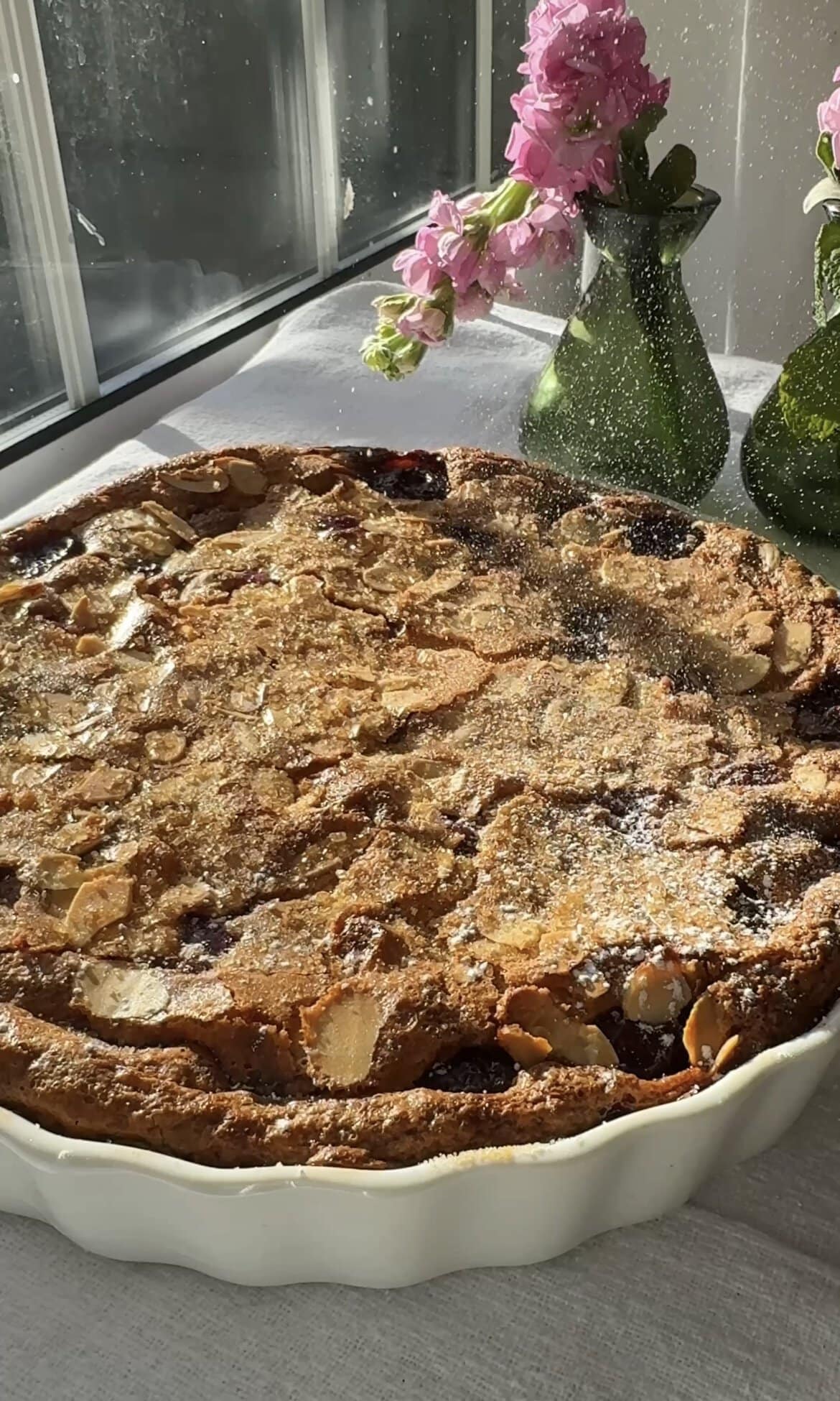 dusting clafoutis aux cerises with icing sugar.