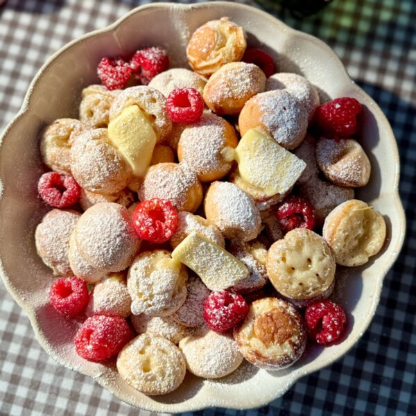 poffertjes in bowl with butter and raspberries.