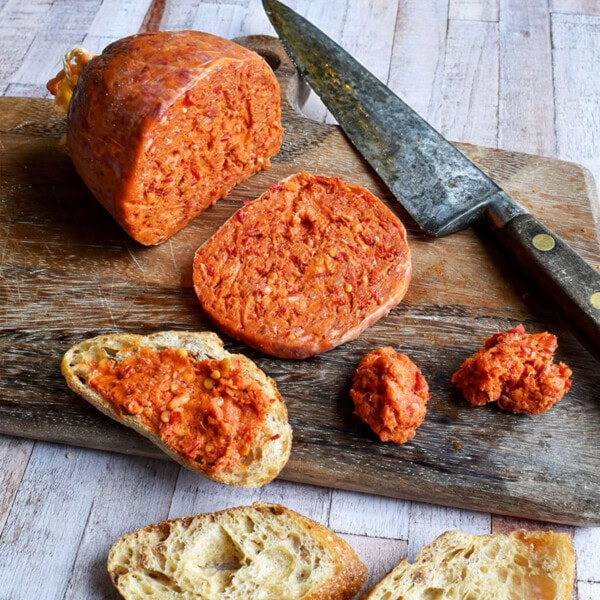 sliced nduja on wooden board and spread onto bread.