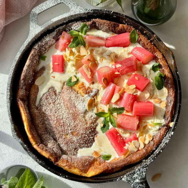 pannukakku in a cast iron pan with whipped mascarpone cream and poached rhubarb.