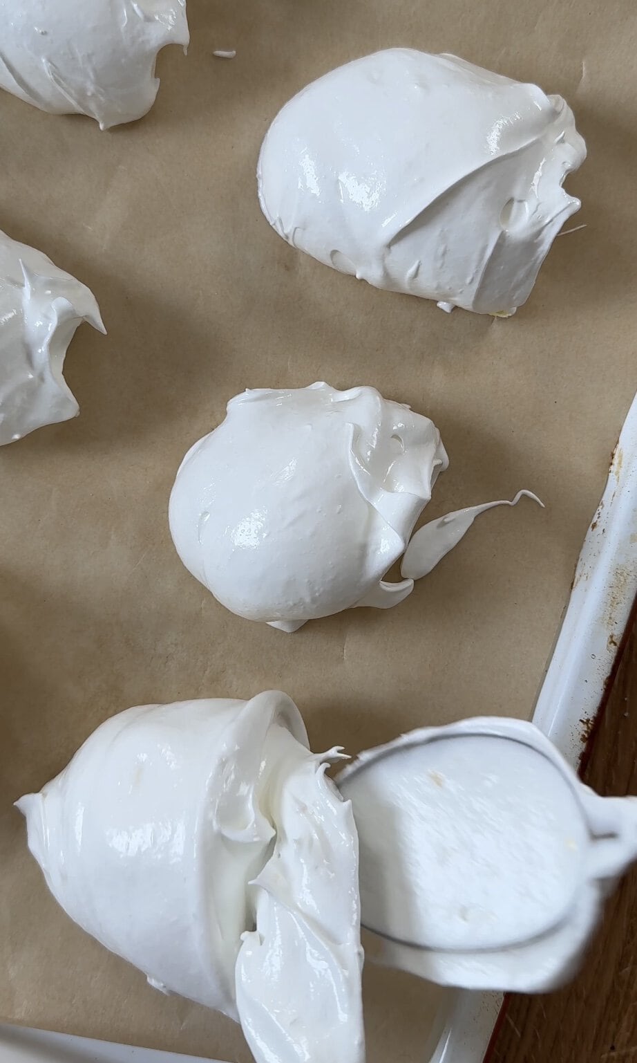 scooping lemon meringues onto baking tray with spoons.