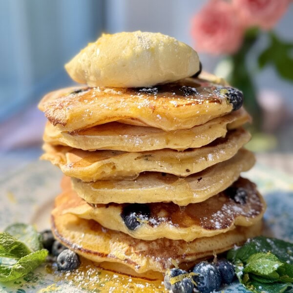 a stack of lemon ricotta blueberry pancakes with whipped honey butter.