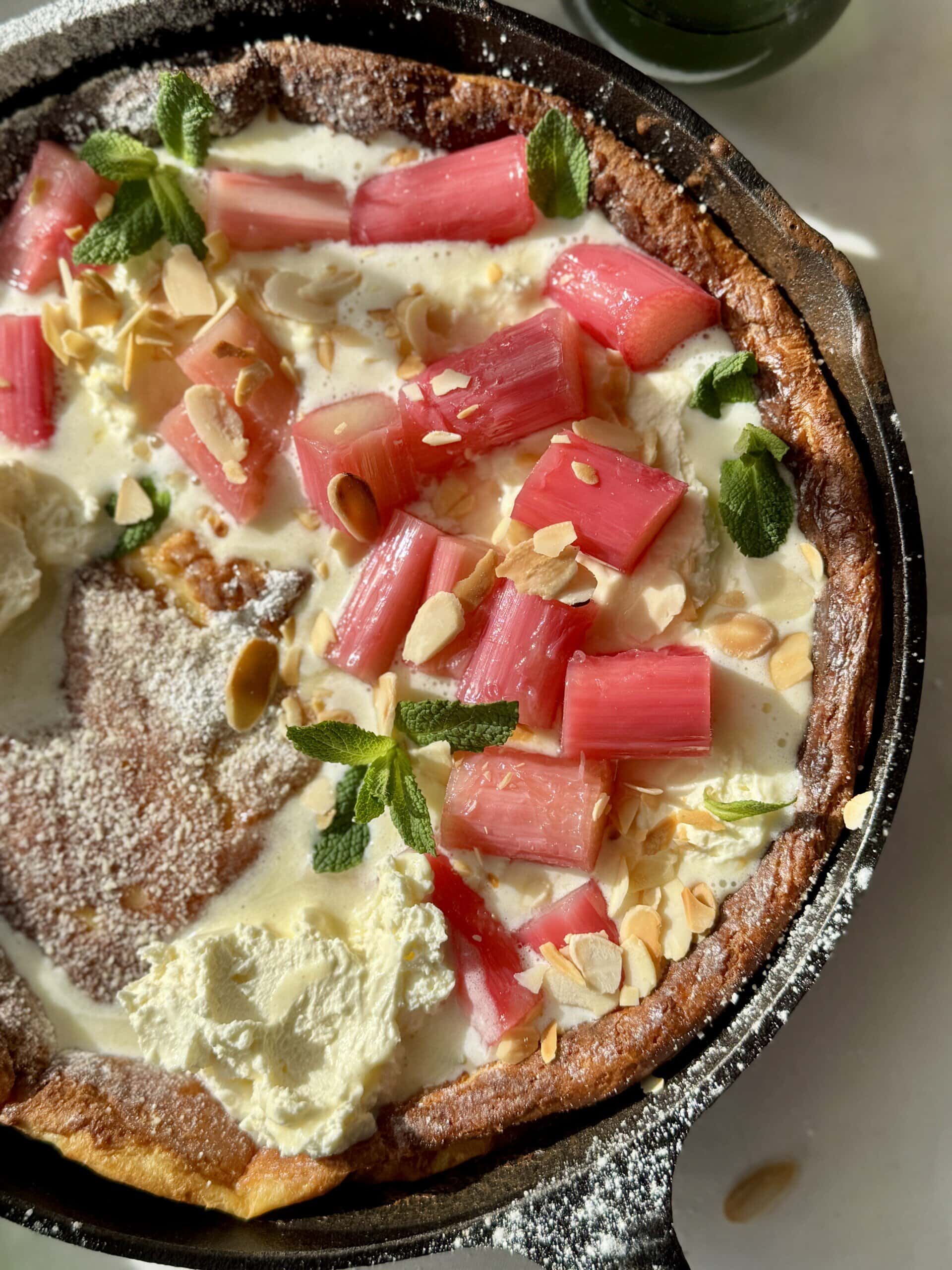 pannukakku in a cast iron pan with whipped mascarpone cream and poached rhubarb.