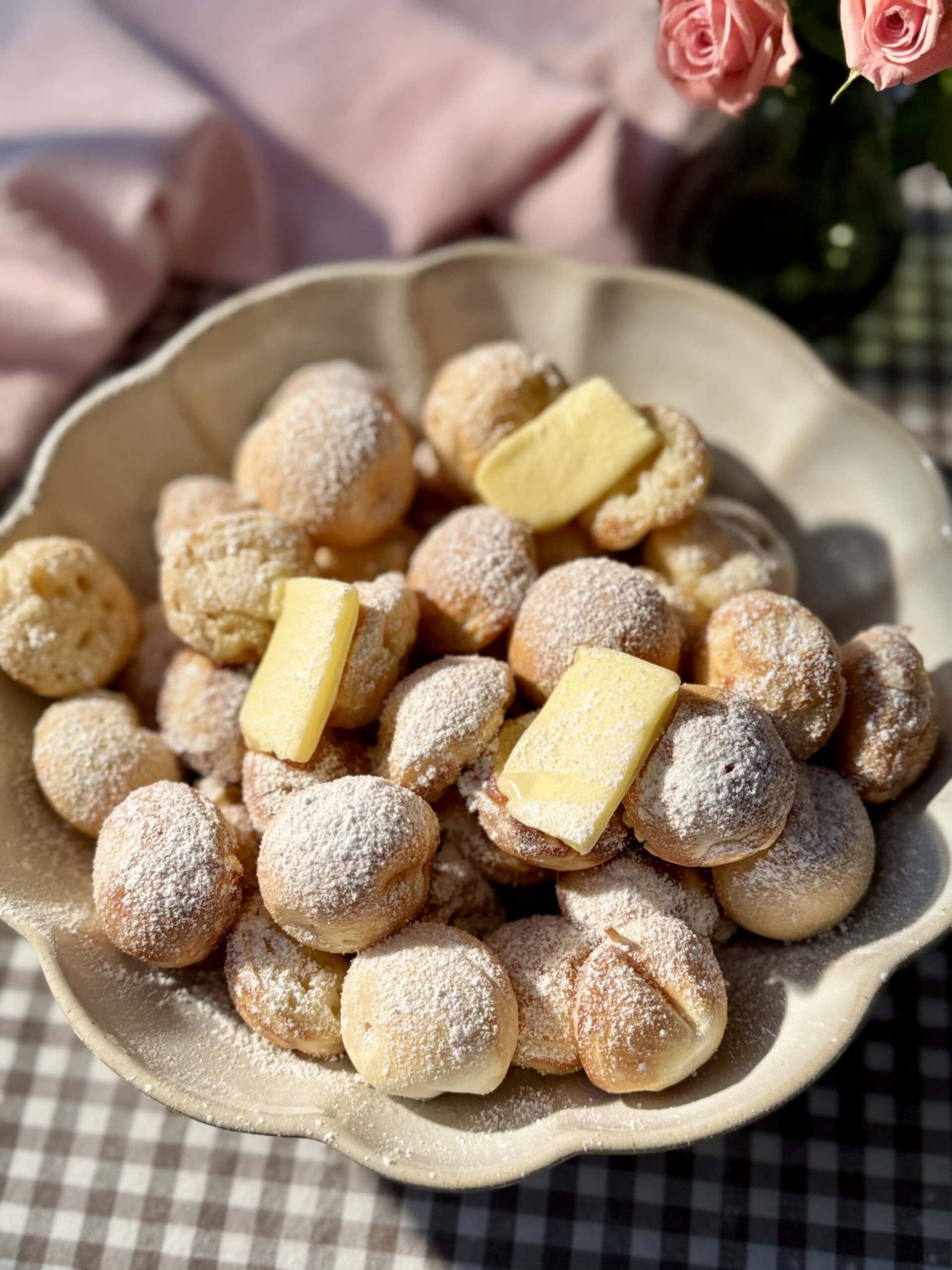 poffertjes in bowl with butter and icing sugar.