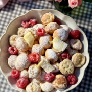poffertjes in bowl with butter and raspberries.
