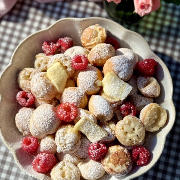 poffertjes in bowl with butter and raspberries.