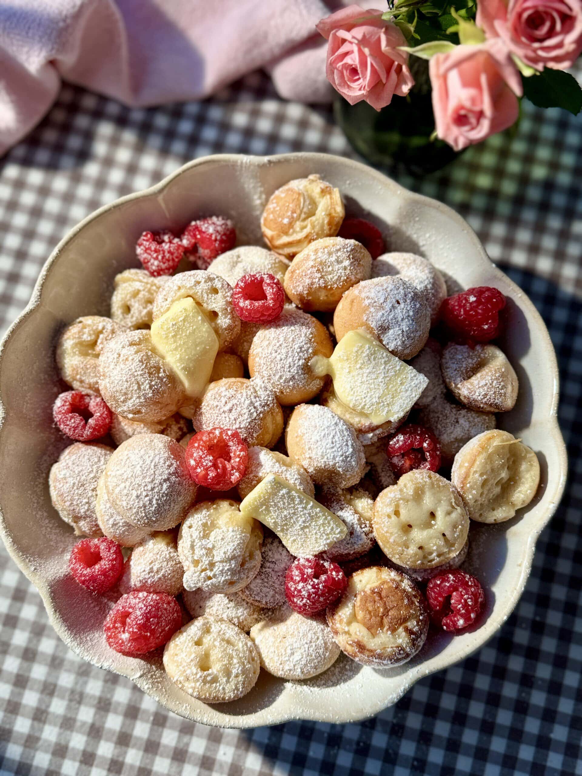 poffertjes in bowl with butter and raspberries.