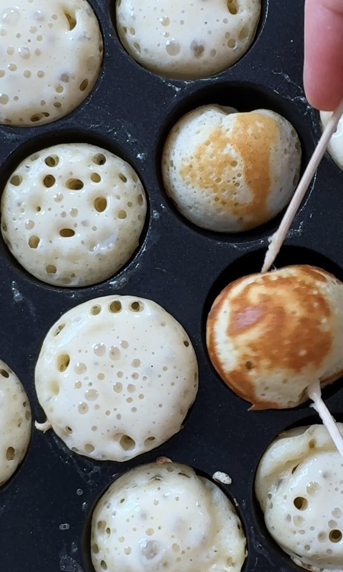 flipping poffertjes in pan.