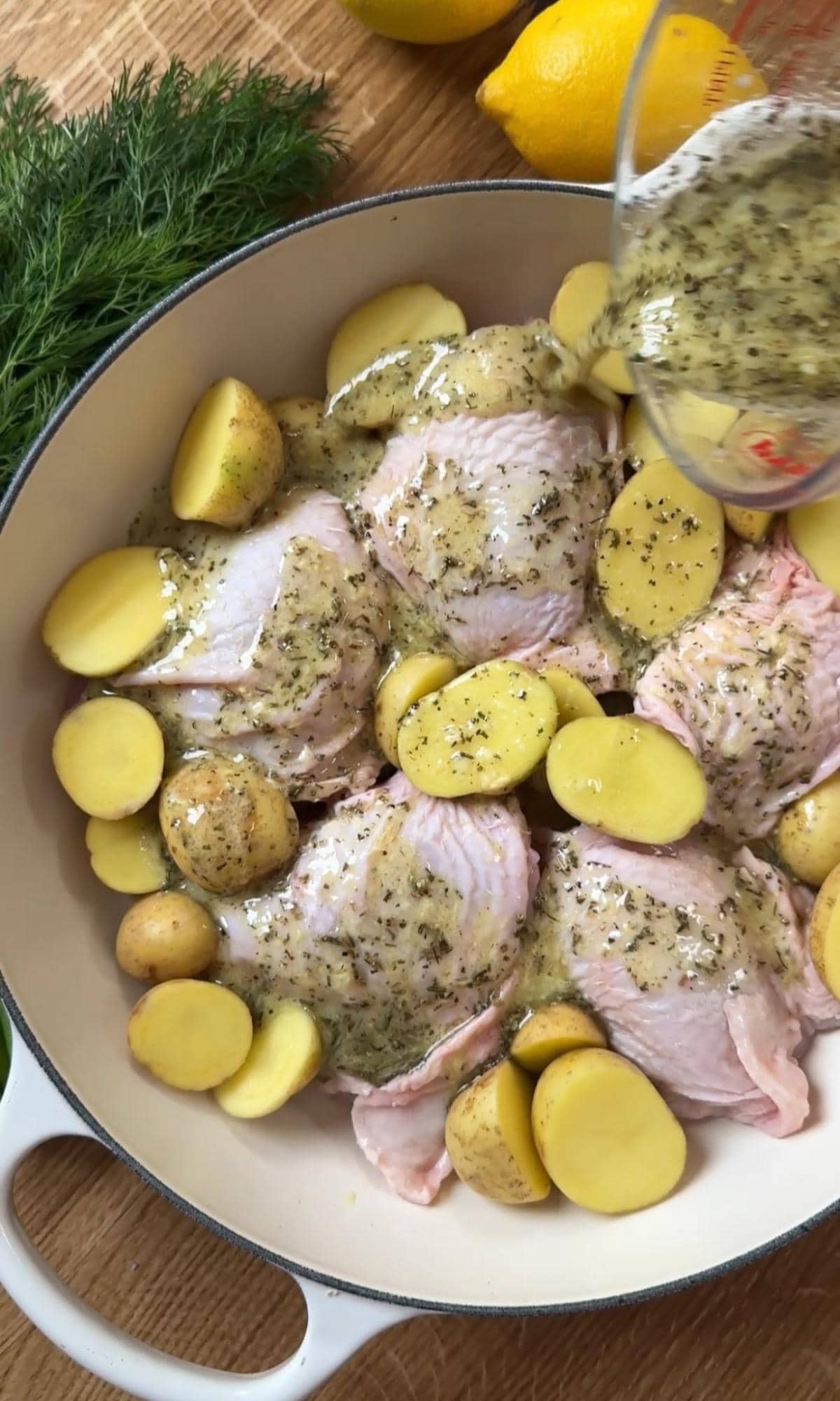 pouring lemon sauce over chicken and potatoes.