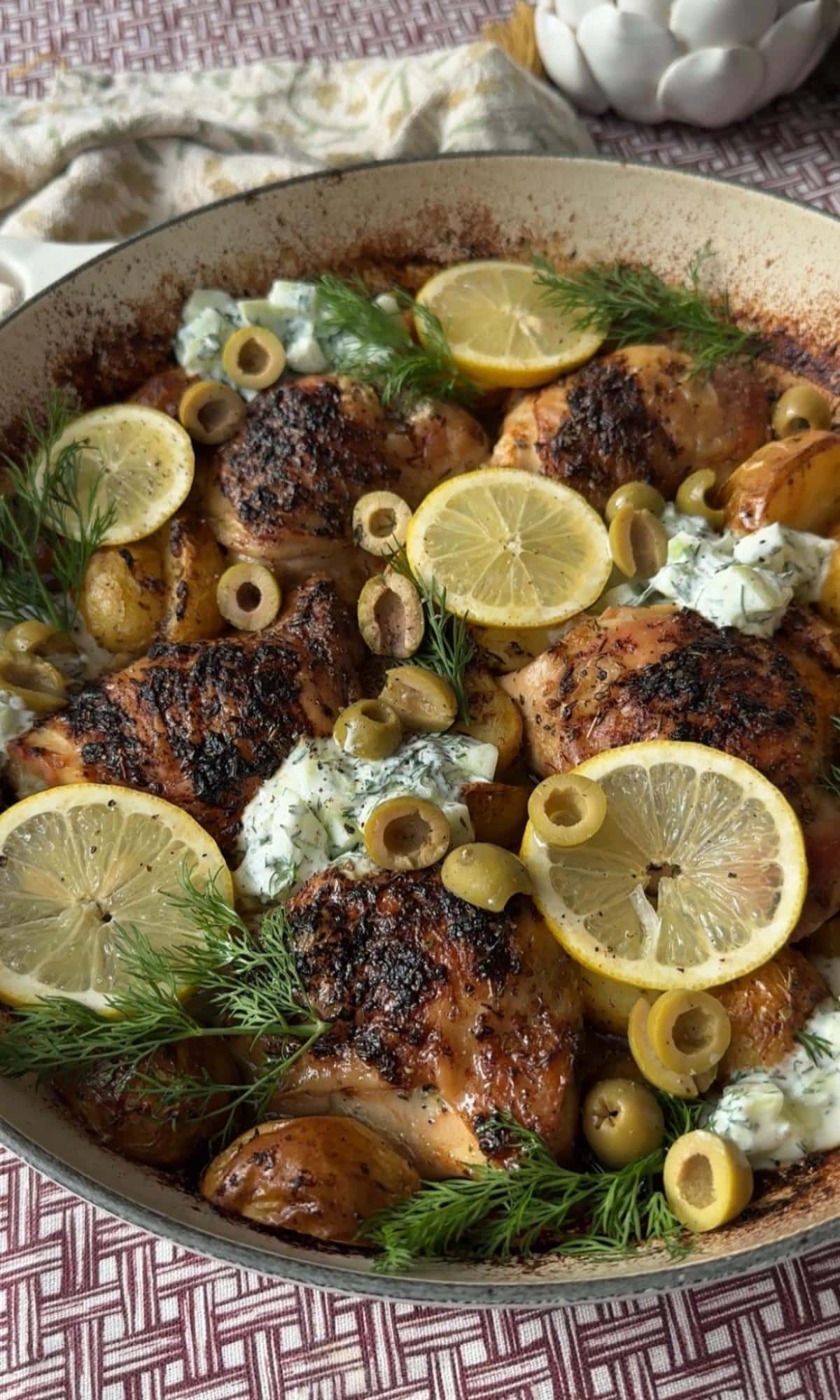 topping greek chicken with lemon potatoes with lemon slices.