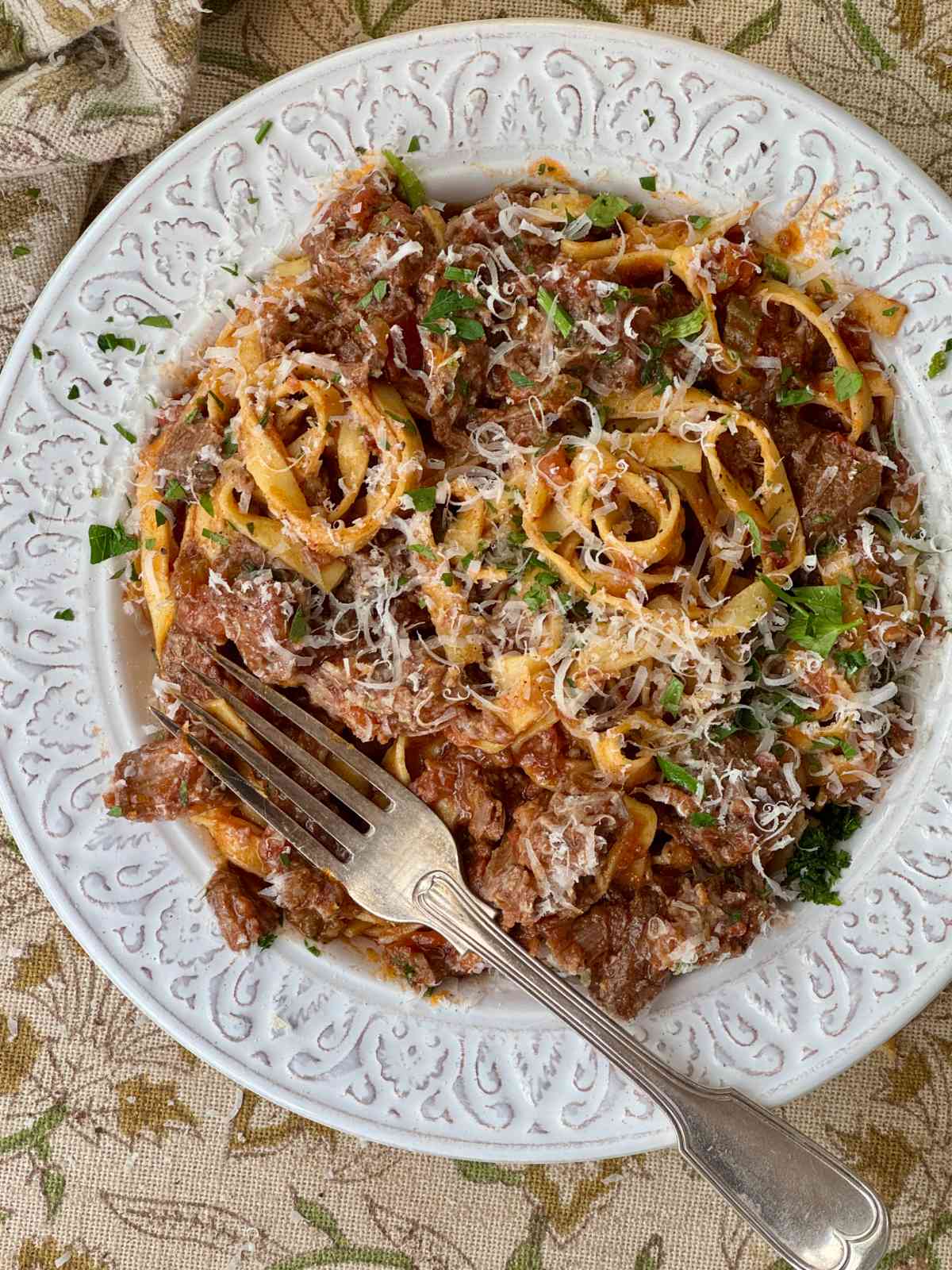 beef shin ragu with tagliatelle in a white bowl.