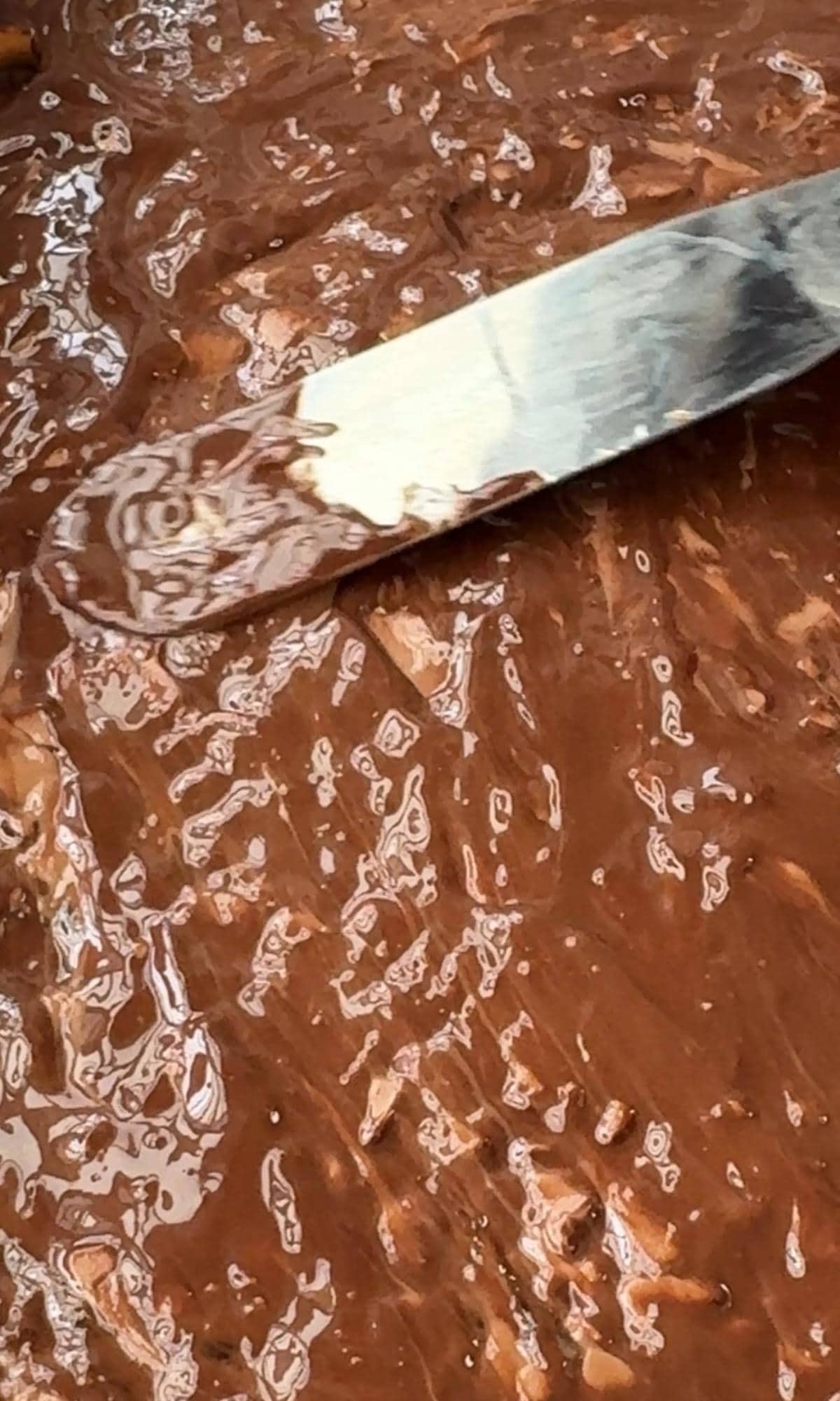 spreading chocolate over the christmas pretzel crack.