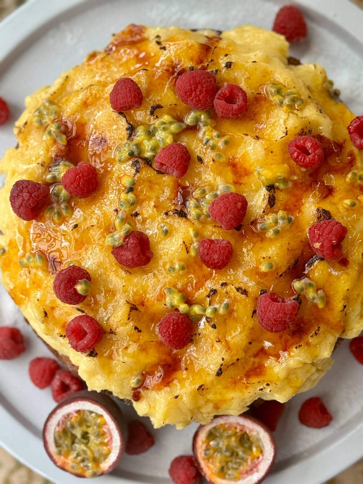 whole creme brulee cake decorated with raspberries and passionfruit.