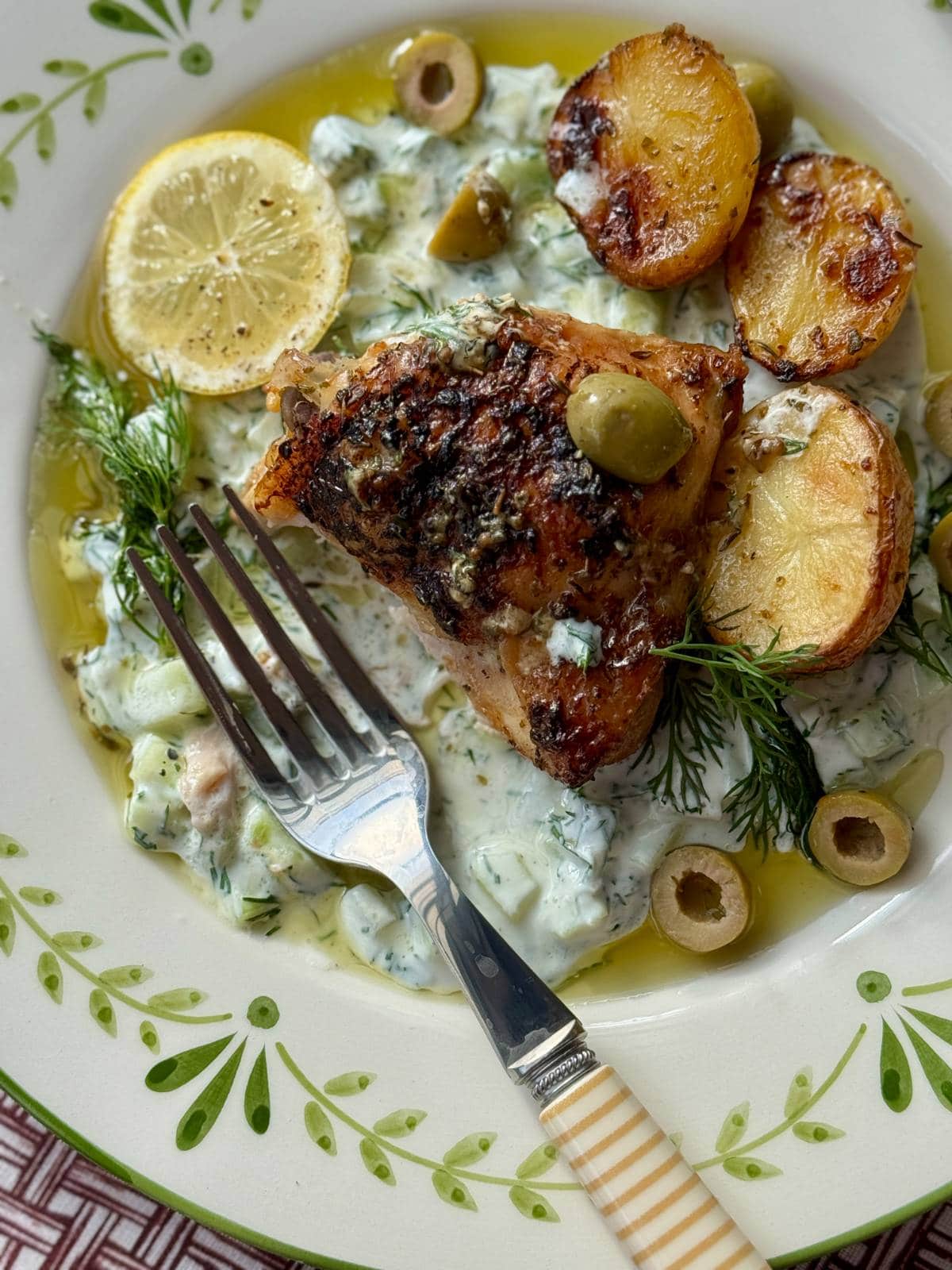 greek chicken lemon potatoes on a white plate.