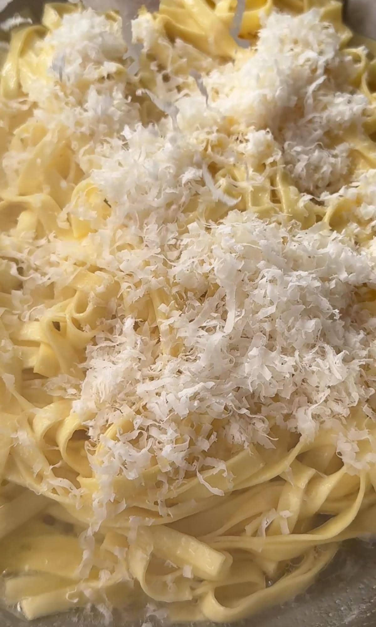 adding parmesan to pasta.