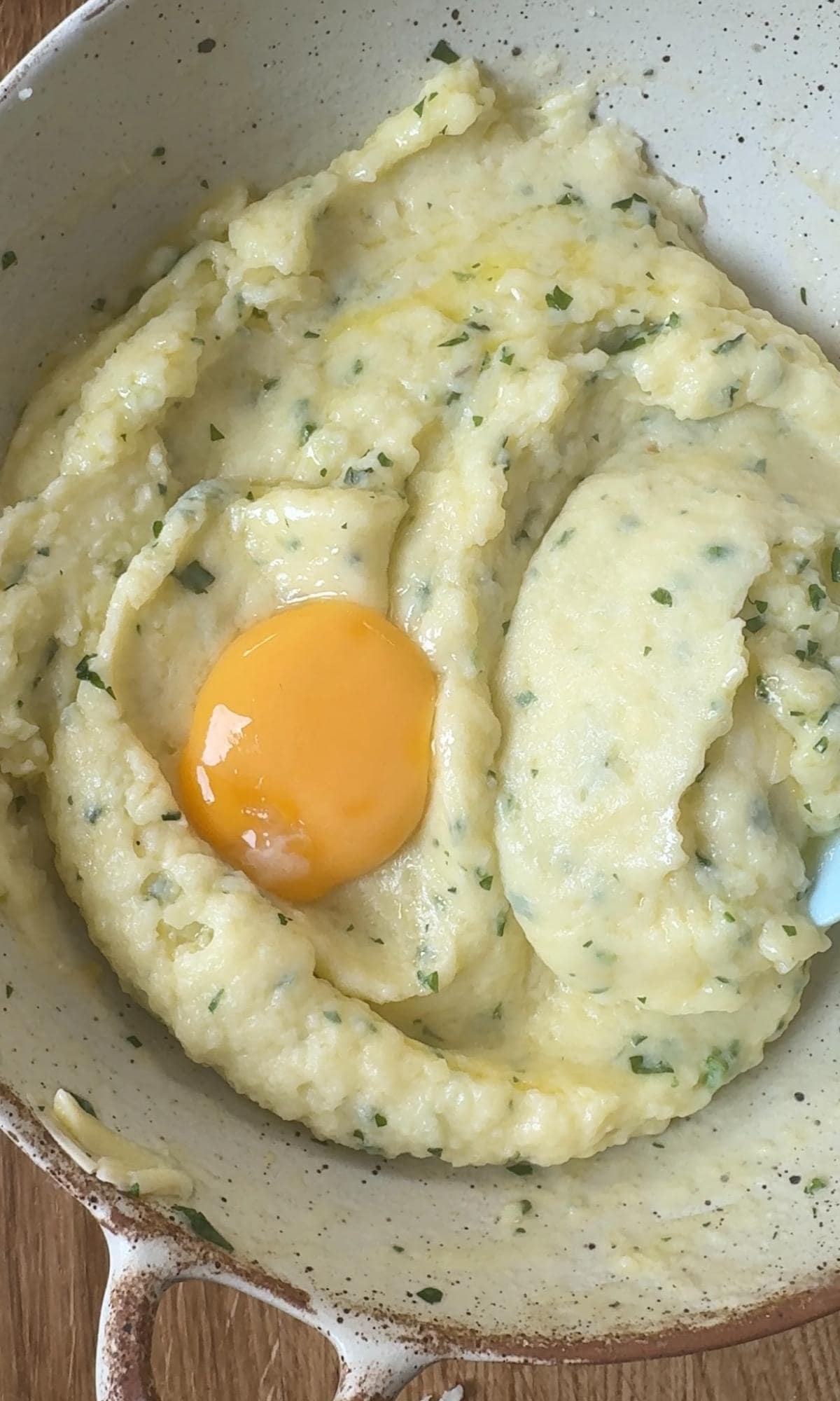 adding egg yolk to mashed potato.