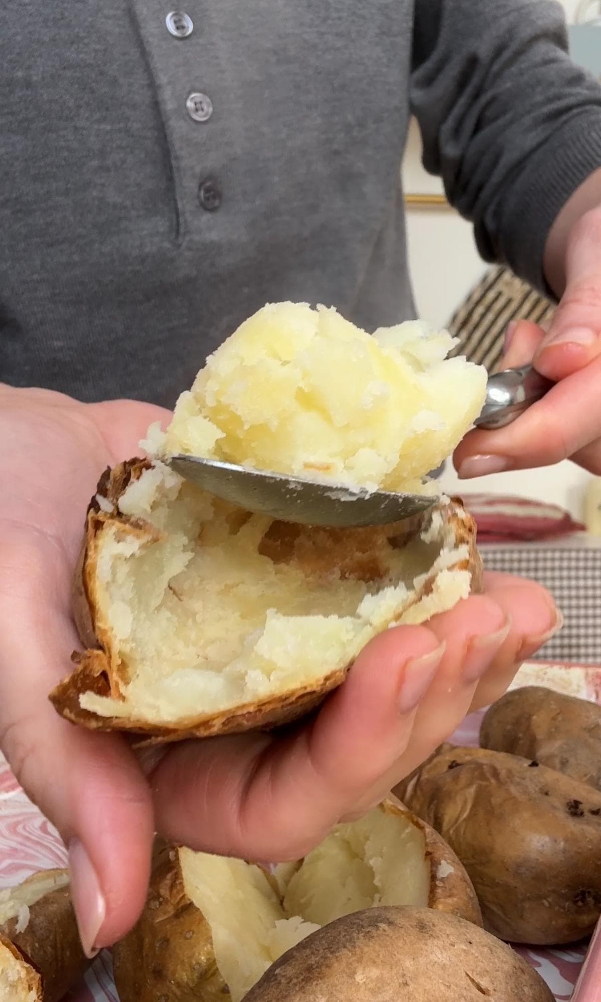 scooping baked potatoes into a bowl.