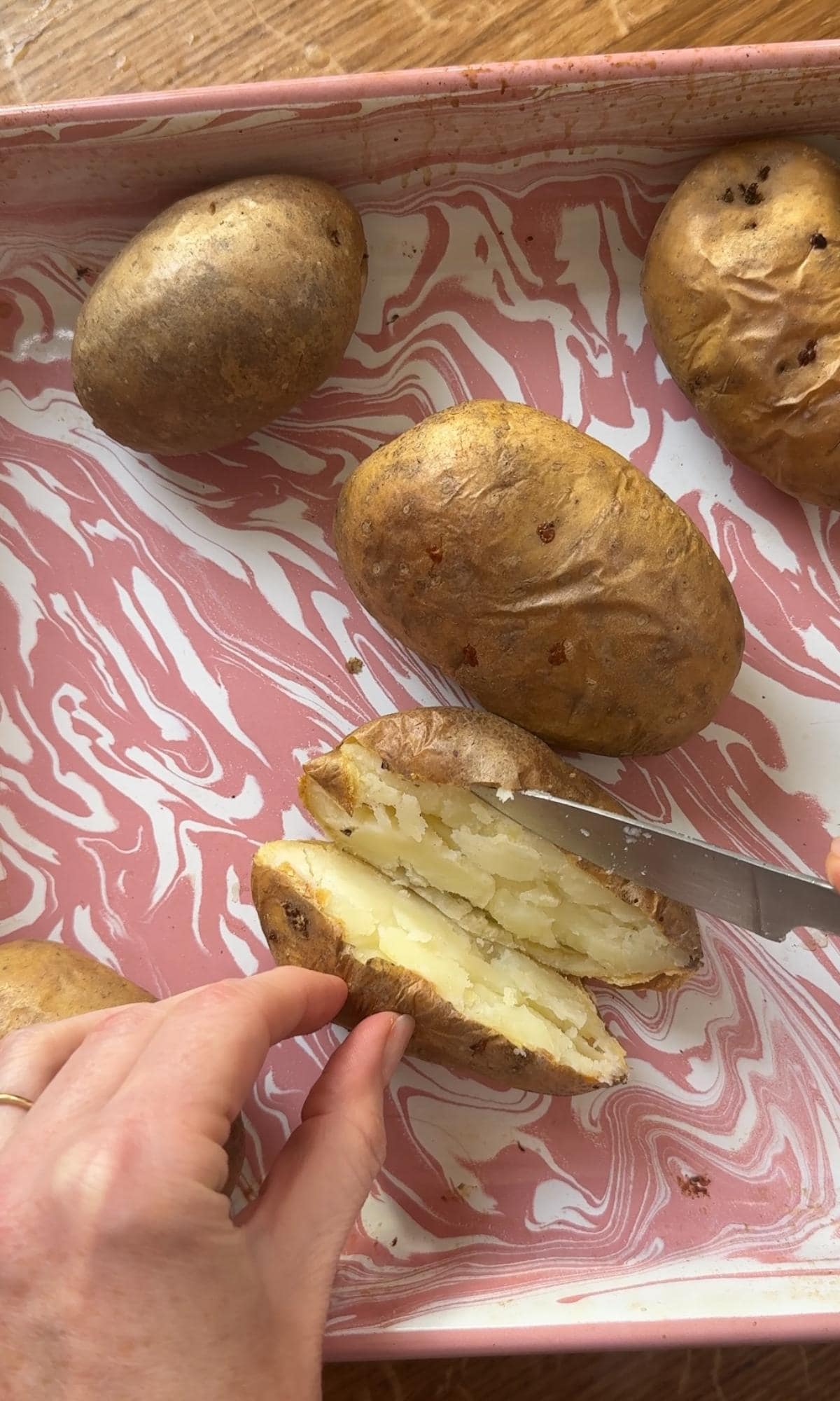 slicing baked potatoes in half.
