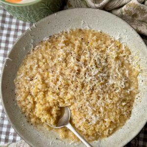 a bowl of creamy pastina with a spoon in the bowl.