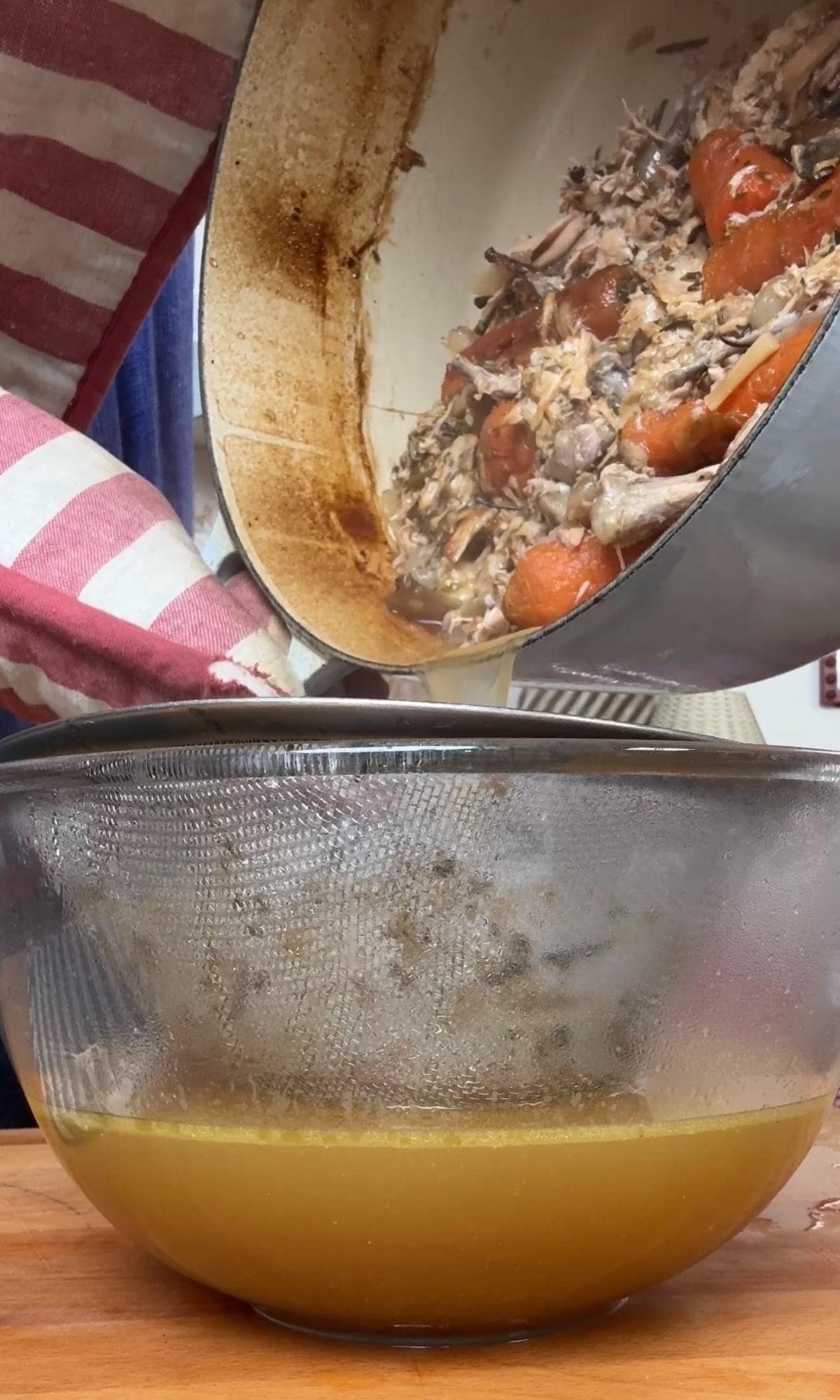 straining homemade chicken stock.