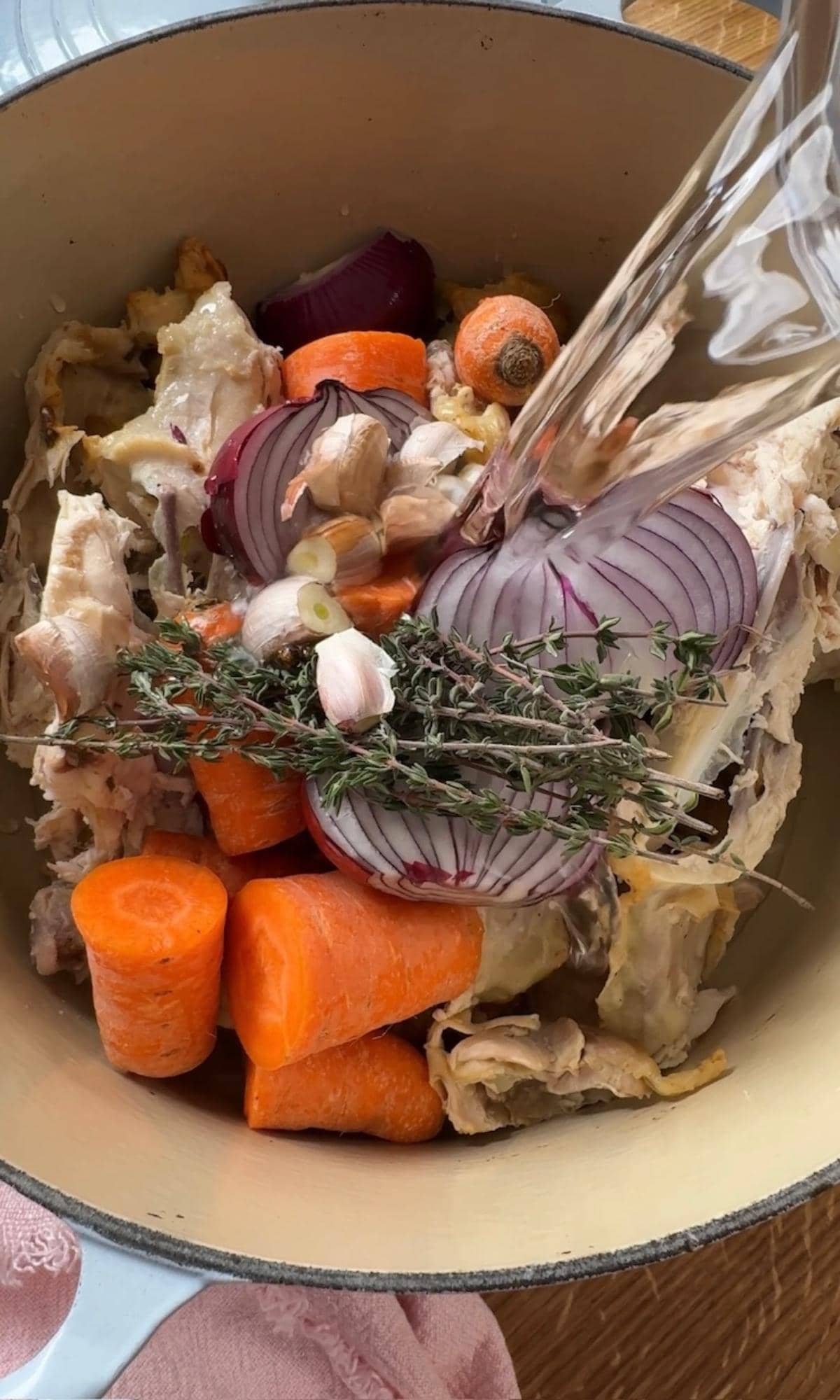 pouring water on chicken carcass and carrots.